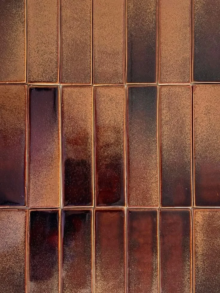 Close-up of a surface covered with glossy, reddish-brown rectangular tiles with darker and lighter shades.