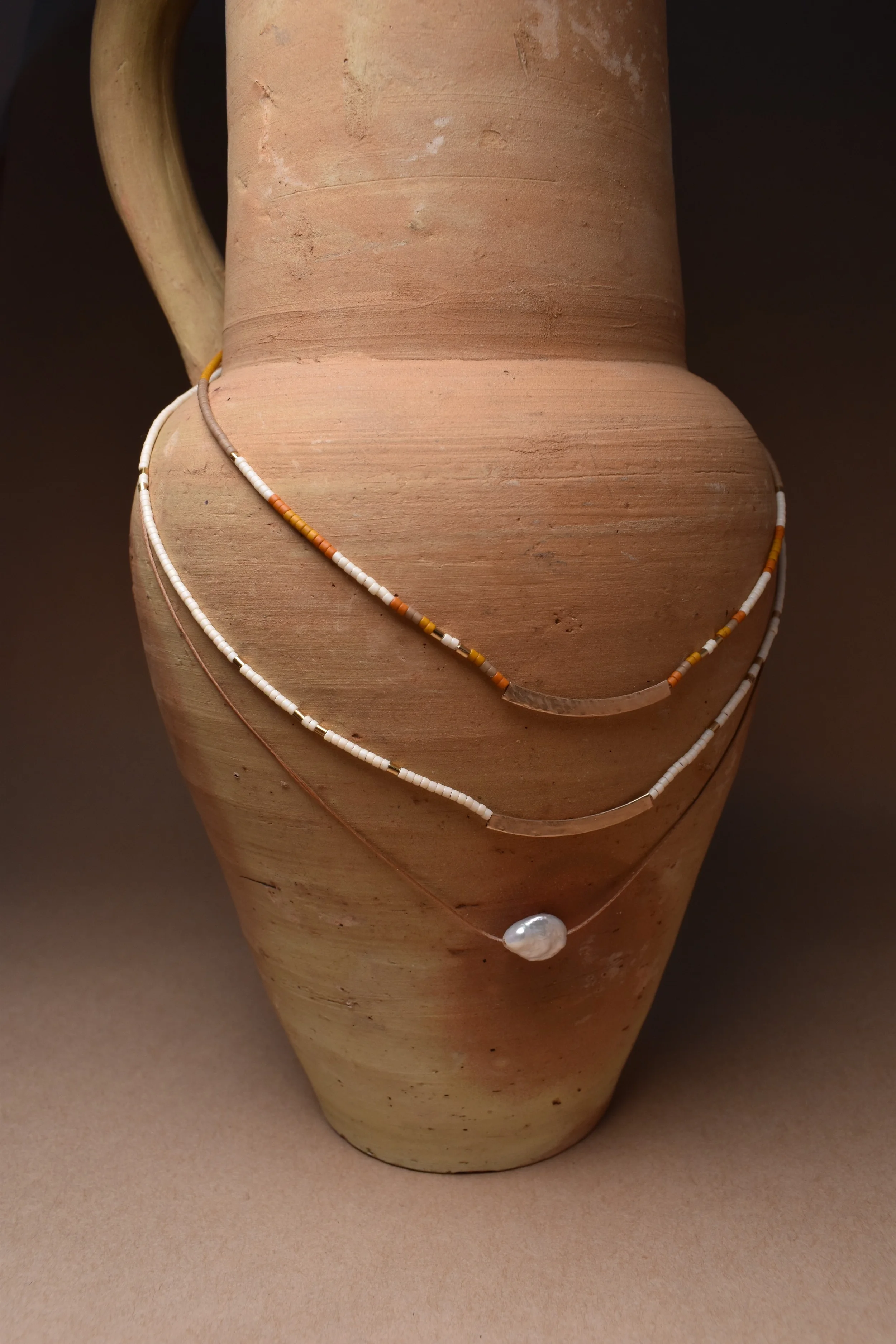 sensai and pearl necklace on vase.webp