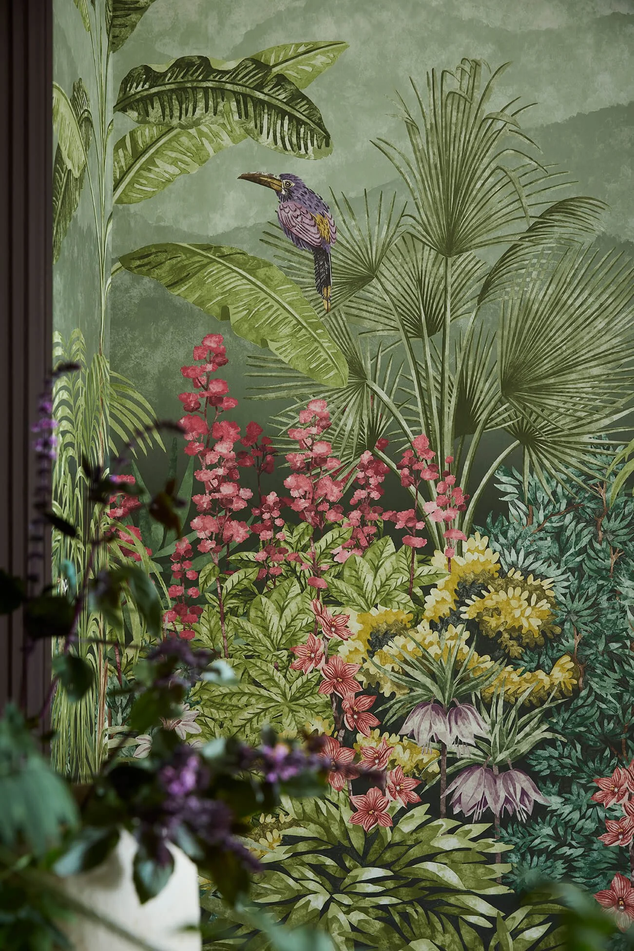 A colorful botanical mural with large green leaves, pink flowers, and a tropical bird.