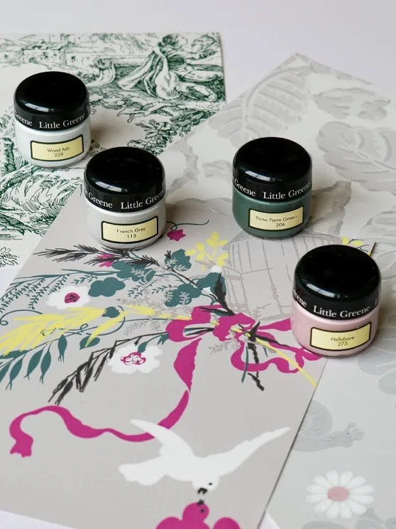 Four small jars of Little Green watercolor pigment on a floral and illustrated paper, with backgrounds of botanical and drawing art.
