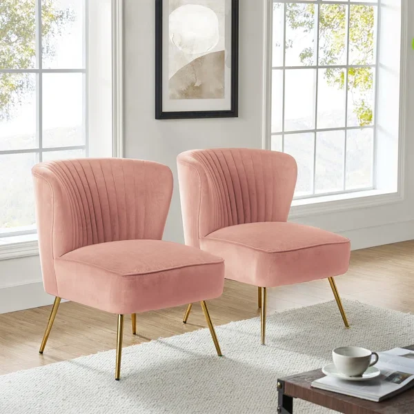 Two pink upholstered chairs with gold legs in a bright room with large windows and a framed abstract art piece on the wall.
