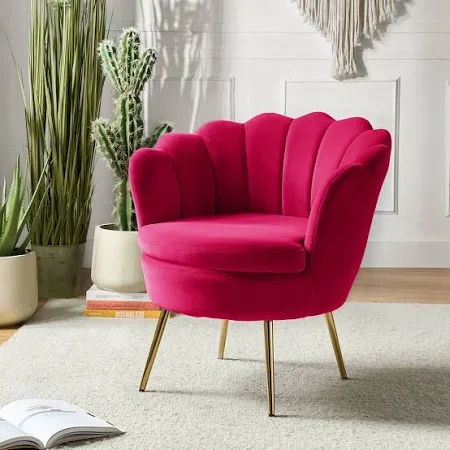 Pink upholstered accent chair with gold legs in a decorated interior with plants and wall decor.