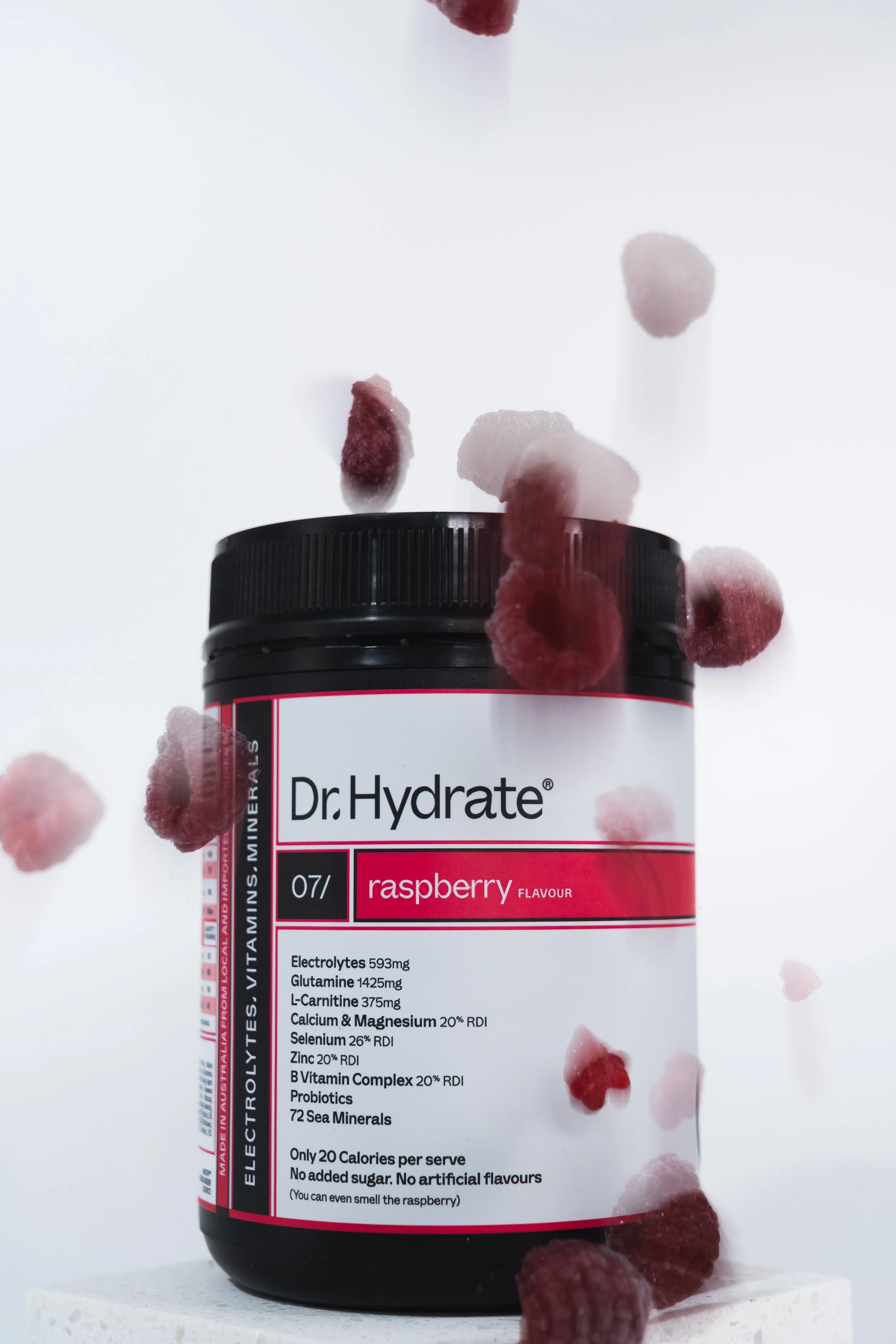A black bottle of Dr. Hydrate raspberry flavored electrolyte supplement with falling raspberries around it on a white background.