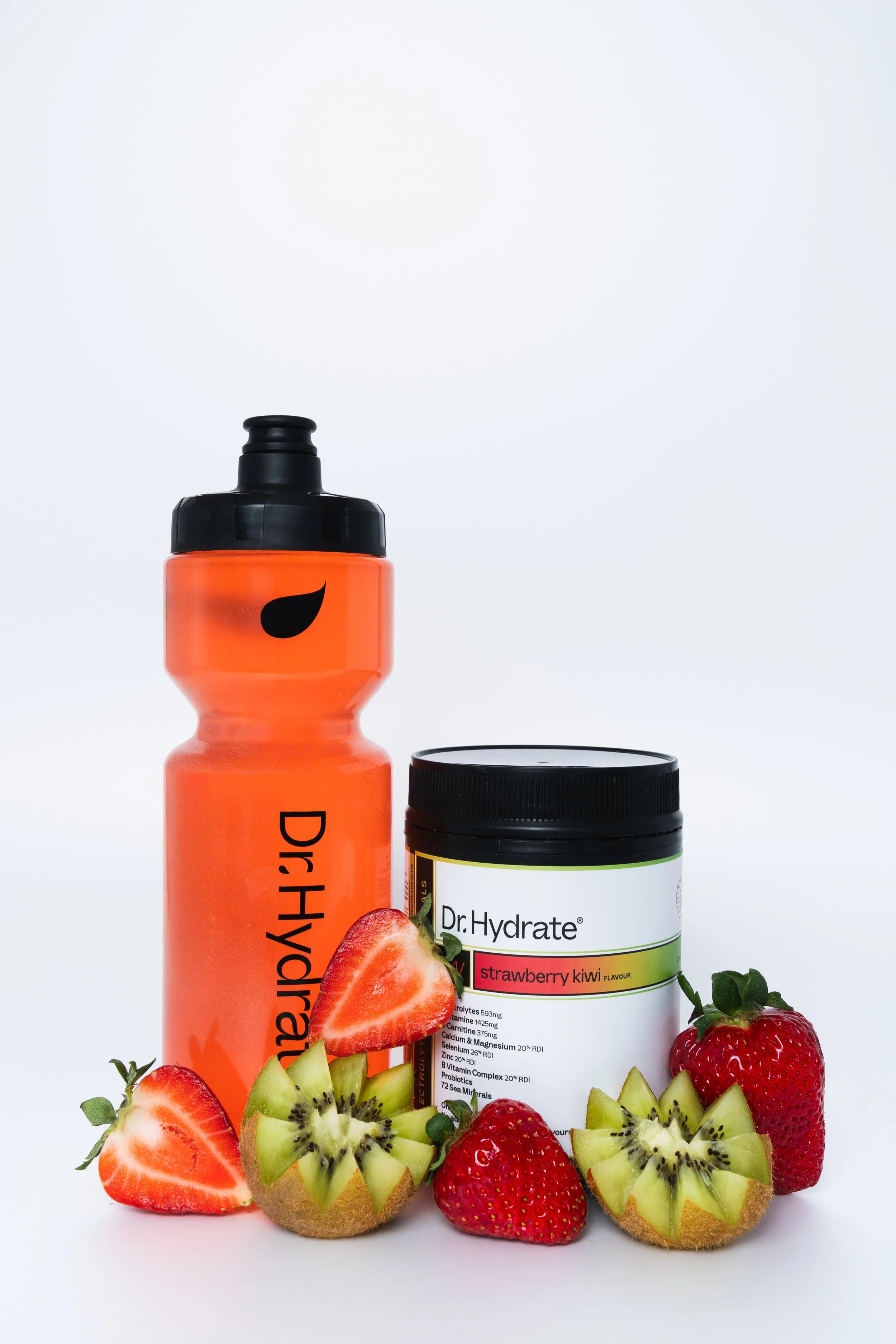 A pink water bottle with a black lid and a peel shape logo, a jar of Dr. Hydrate strawberry kiwi flavored supplement, several strawberries, and sliced kiwi fruit, all arranged on a white background.