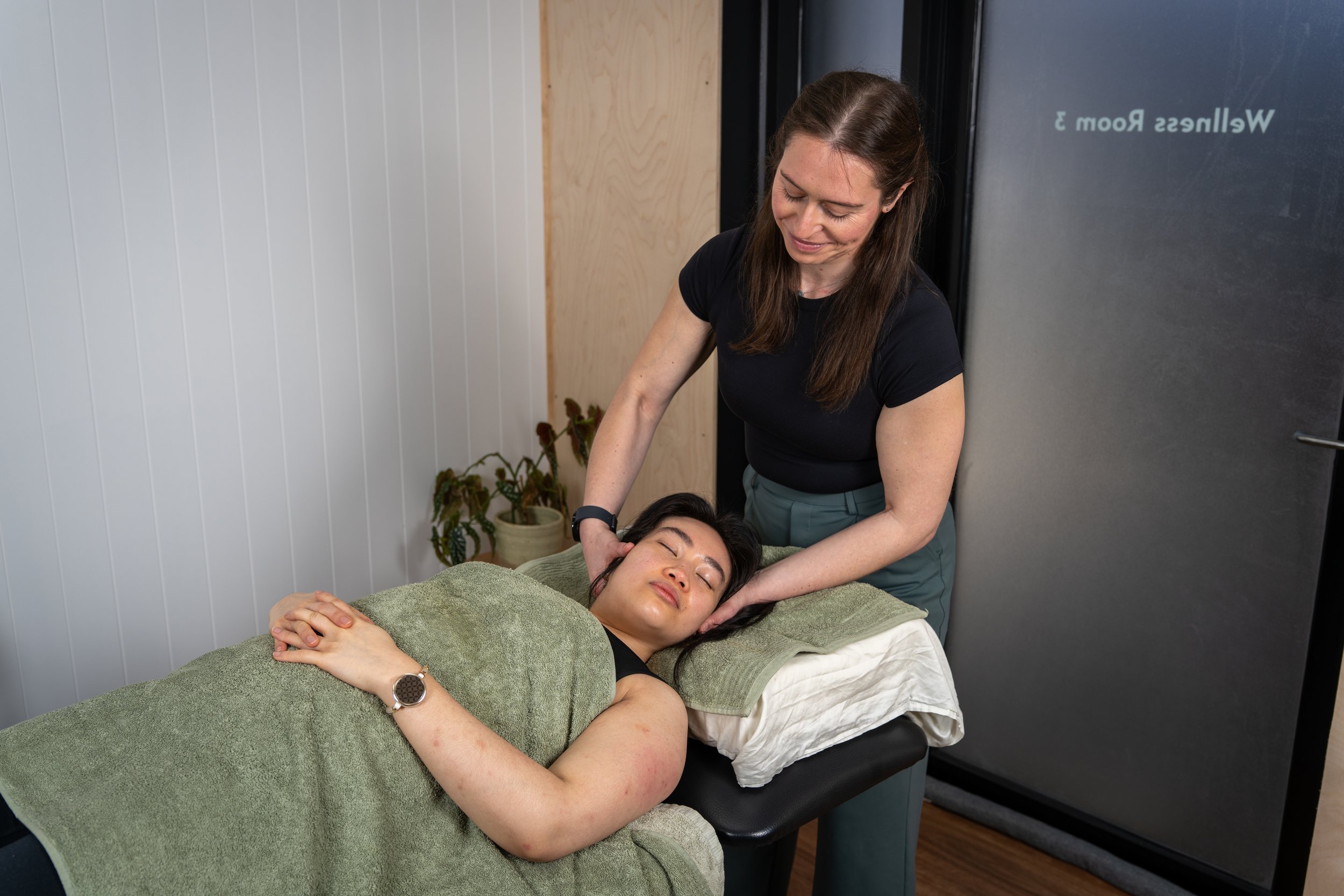 A client/patient smiling as she receives a neck adjustment/manipulation from an Osteopath in an Osteopathy clinic.