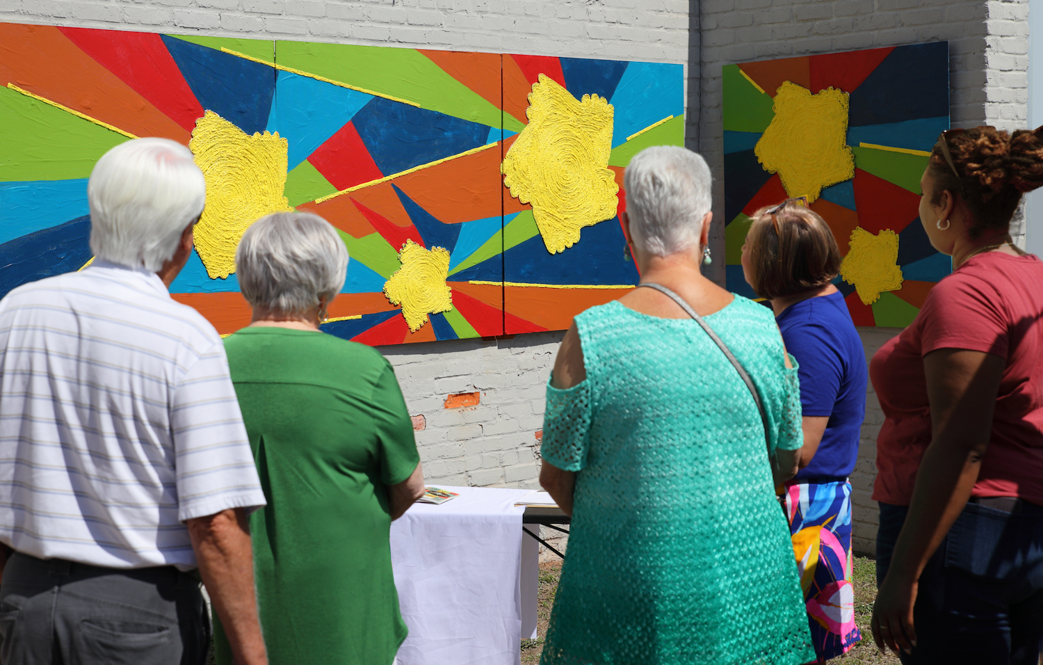 April 2022: Visitors discussing the tile mural installation with leadership from The Greater Lake City Community Resource Center - the two women on the right side of the photo. The intention was for them to have a table at the event because it is cha