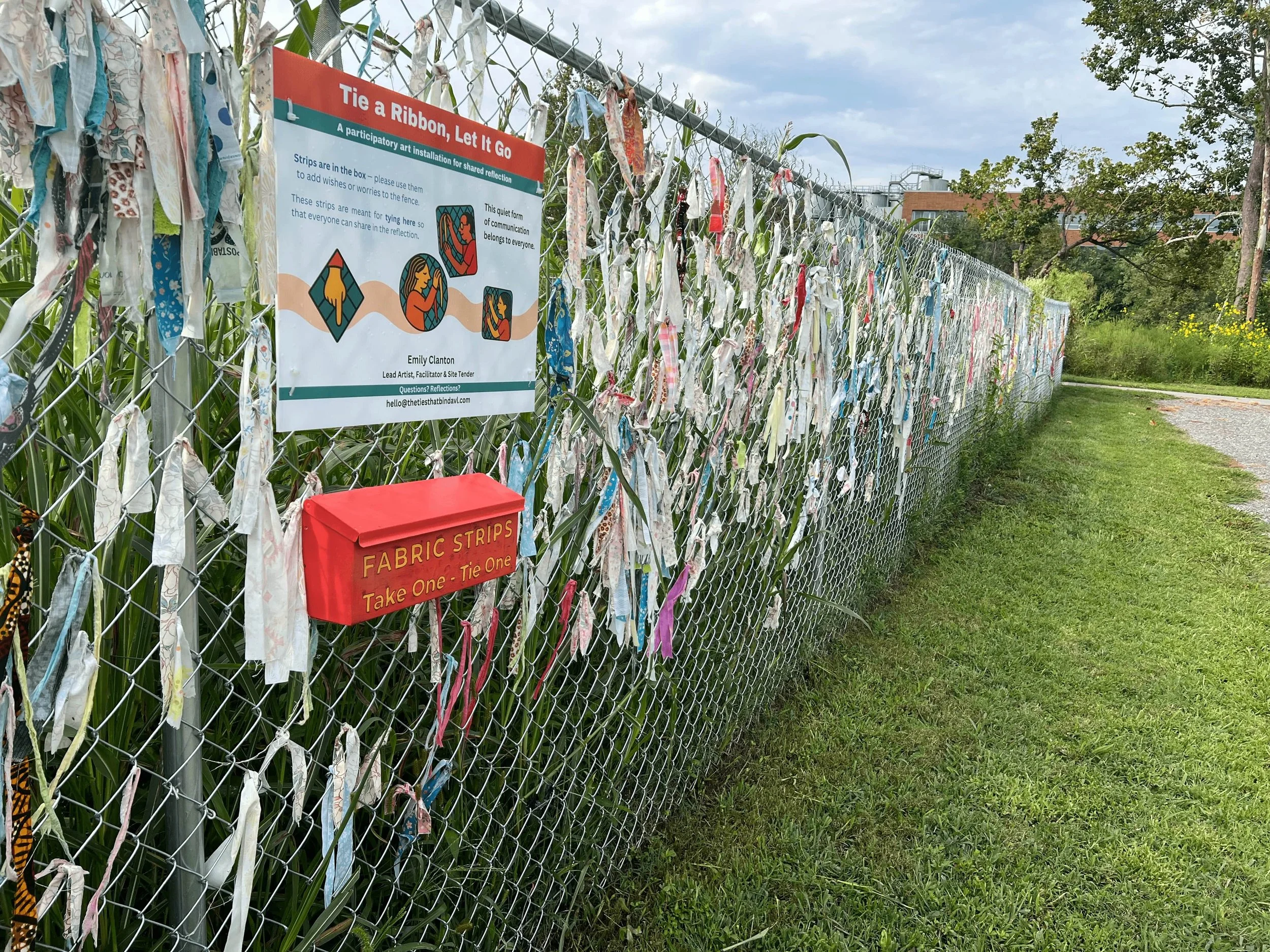 9/29/25 – Day 134:
Detail view of the fence installation showing fabric strips, signage, and a hand-painted mailbox that allows passersby to select and contribute repurposed cotton strips.