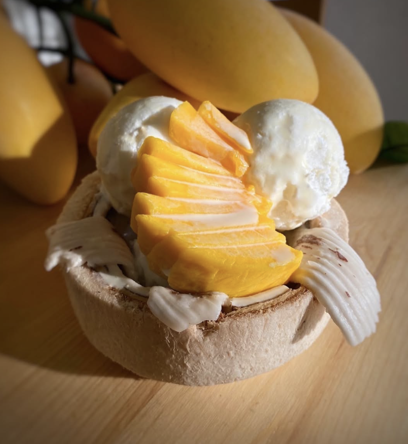 Banana pudding with sliced bananas and vanilla ice cream served in a cup, with whole bananas in the background.