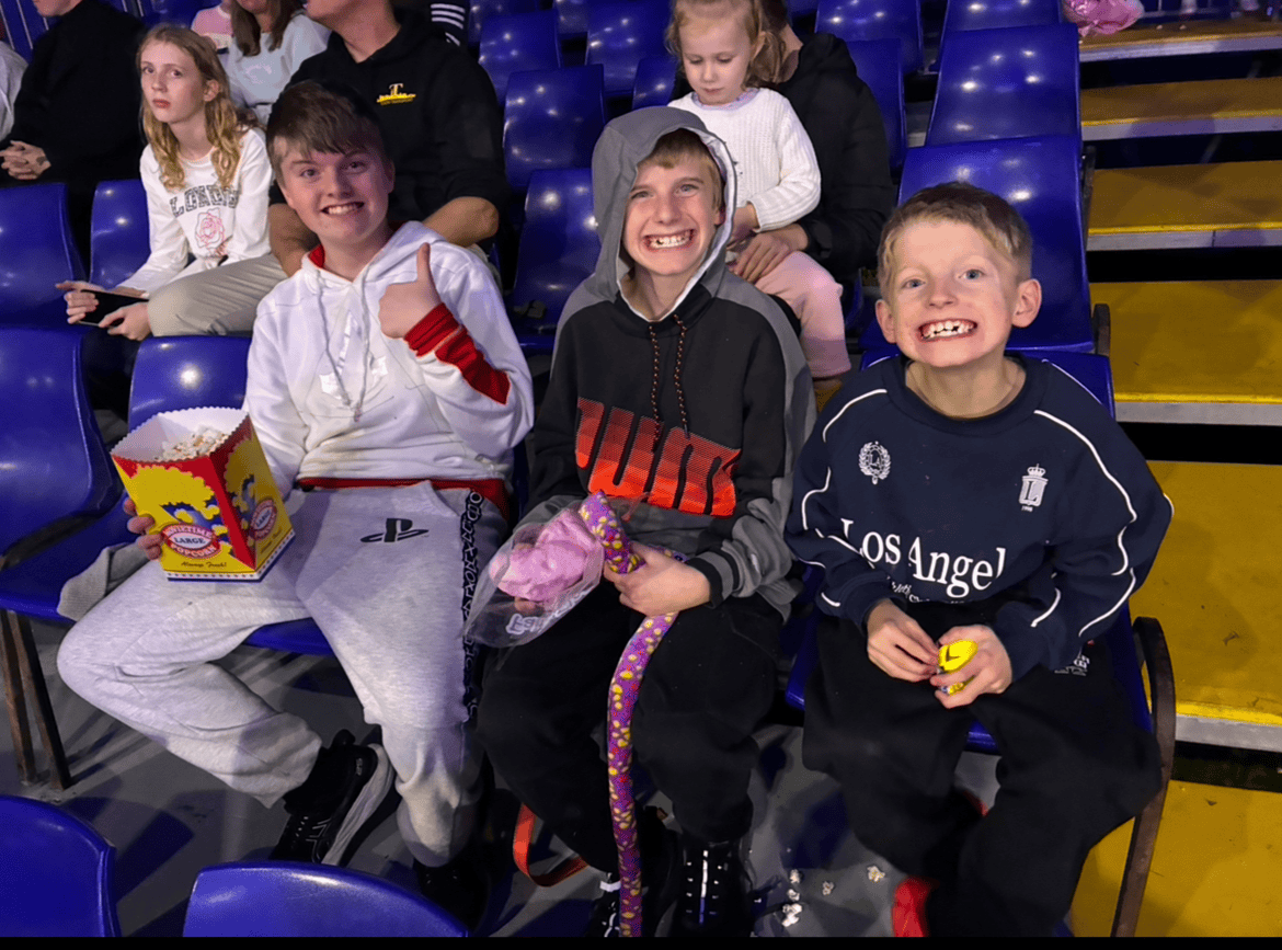 Children sitting in theater seats, smiling and holding snacks and toys.