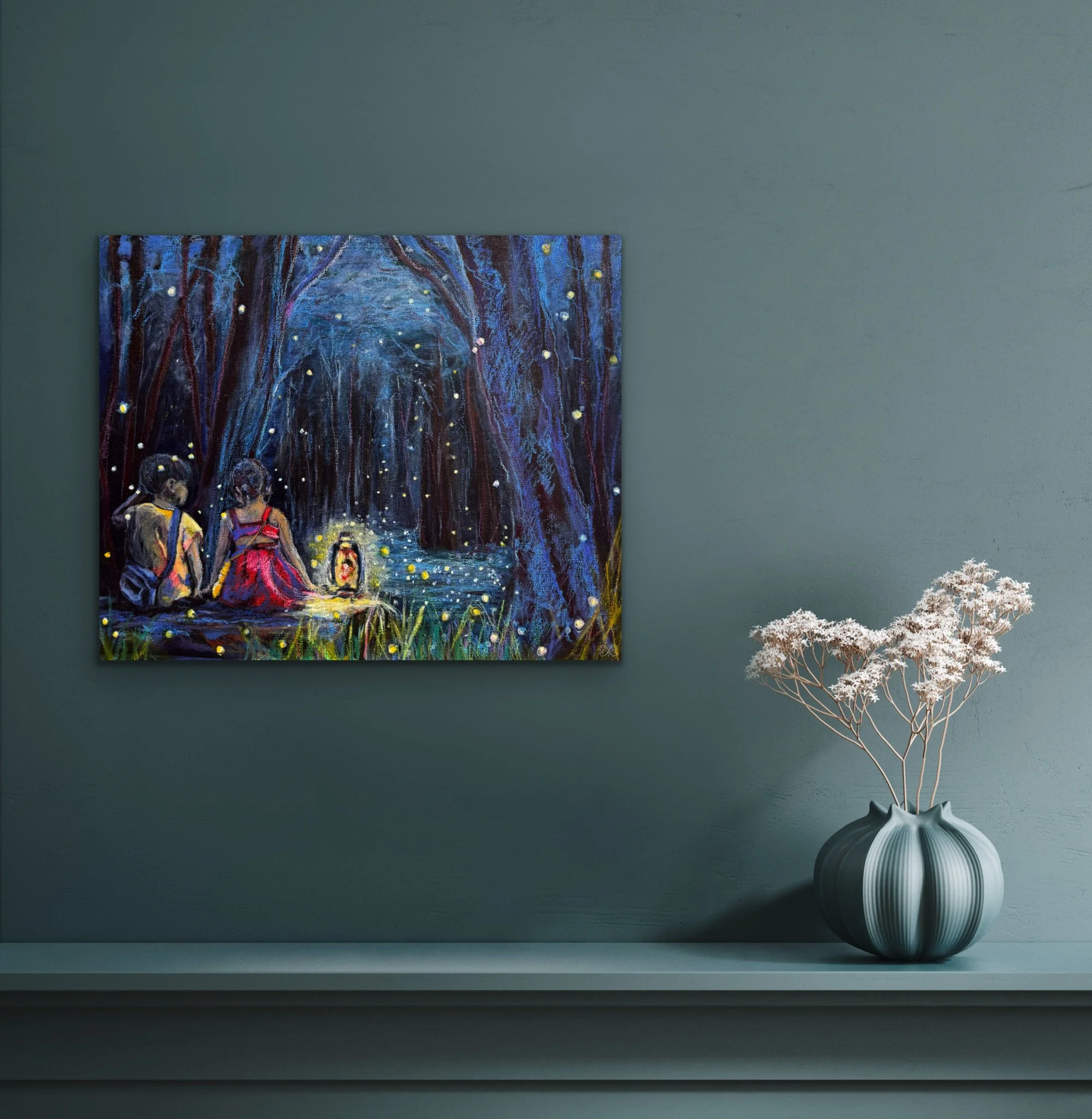 A dark green wall with a framed painting depicting a path through a forest at night illuminated by fireflies, and a ceramic vase with a white and black stripe pattern holding dried flowers placed on a white shelf below the painting.