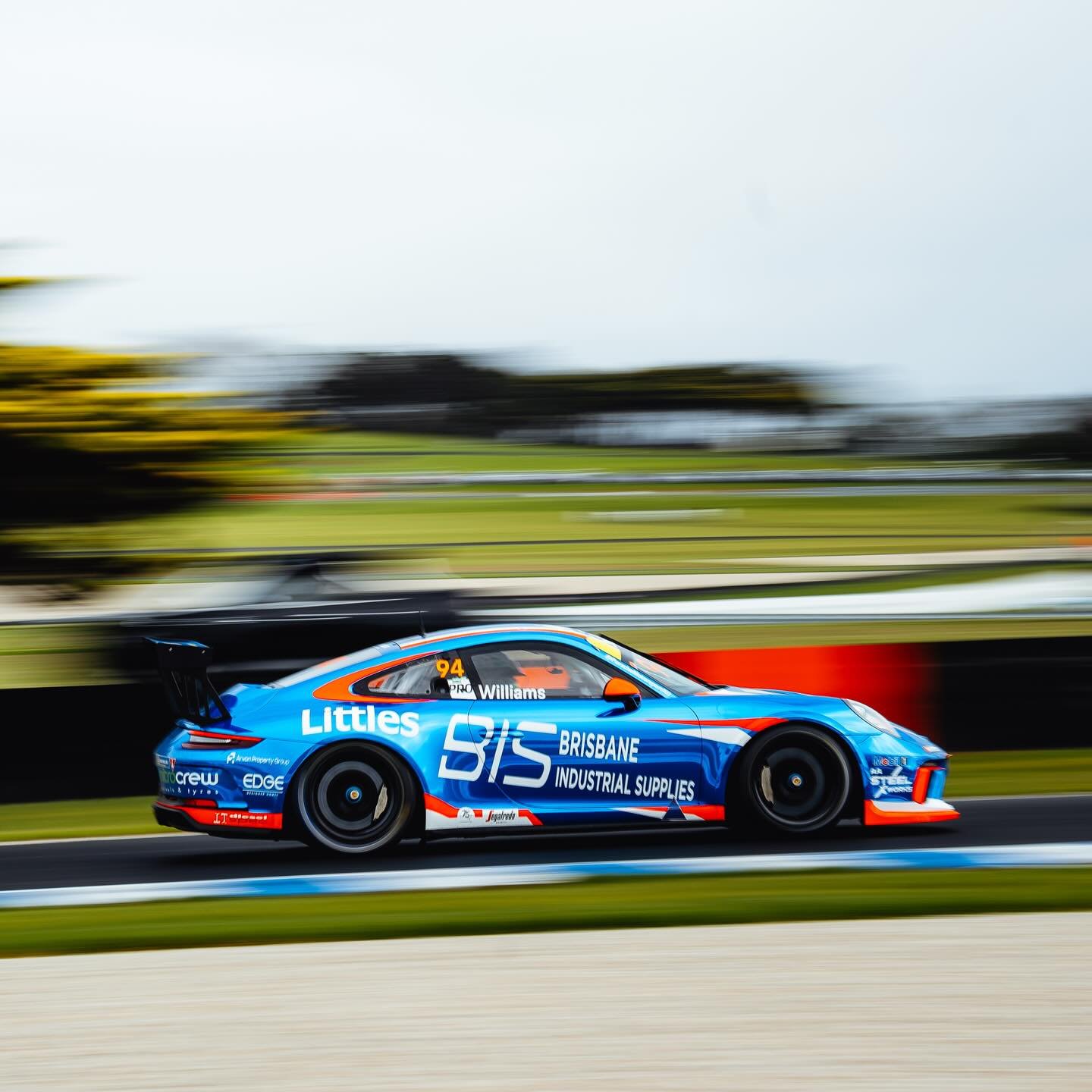 A blue race car speeding on a race track, motion blur background.