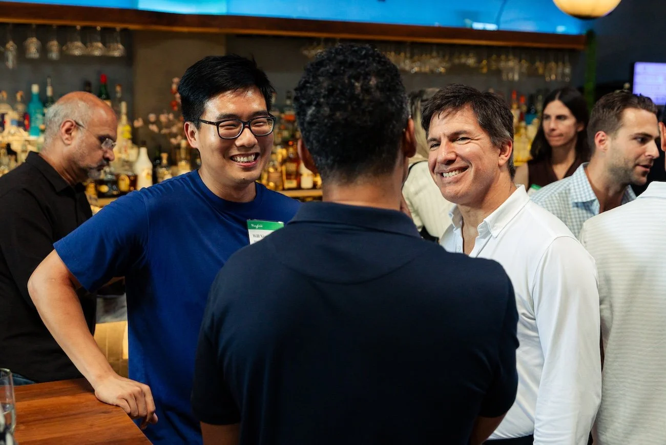 Group of people socializing at a bar in a social setting, engaging in conversation and smiling.