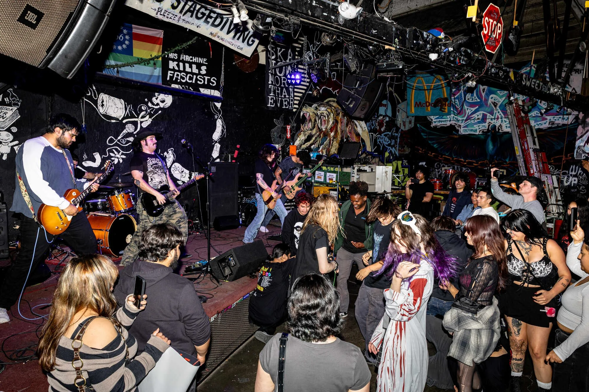 A live band performs on stage at a music venue with a small crowd dancing and enjoying the show.