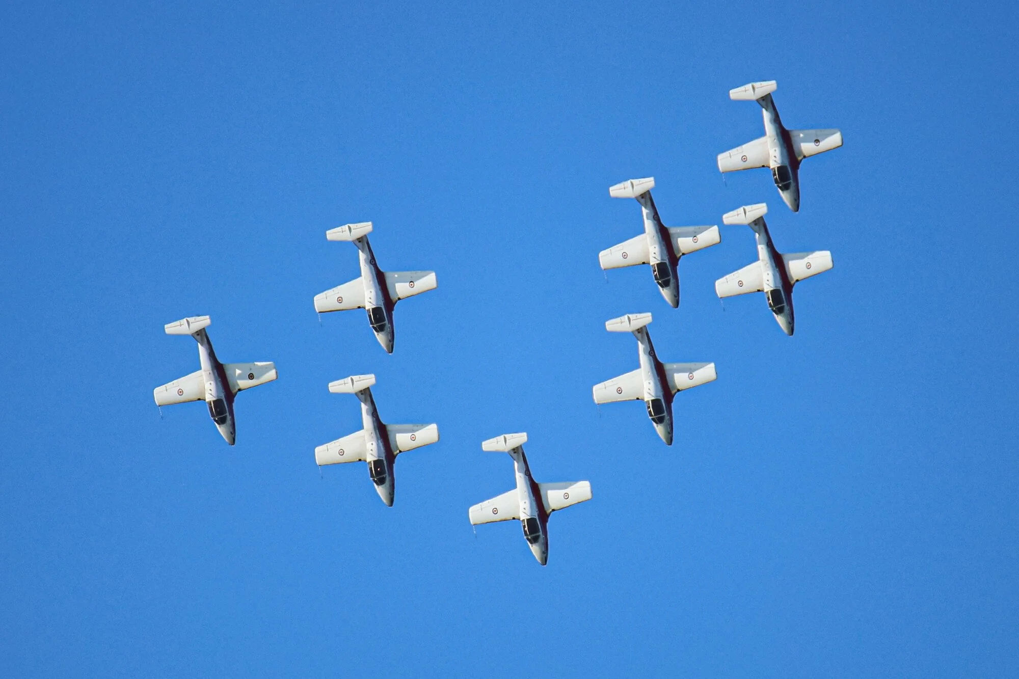 Six fighter jets flying in formation against a clear blue sky.