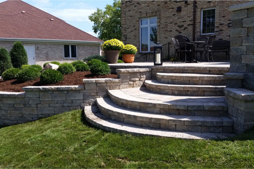 Curved stone paver steps leading down to backyard lawn.png
