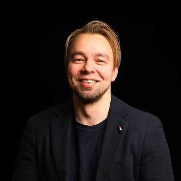 Henkilö hymyilee mustalla taustalla