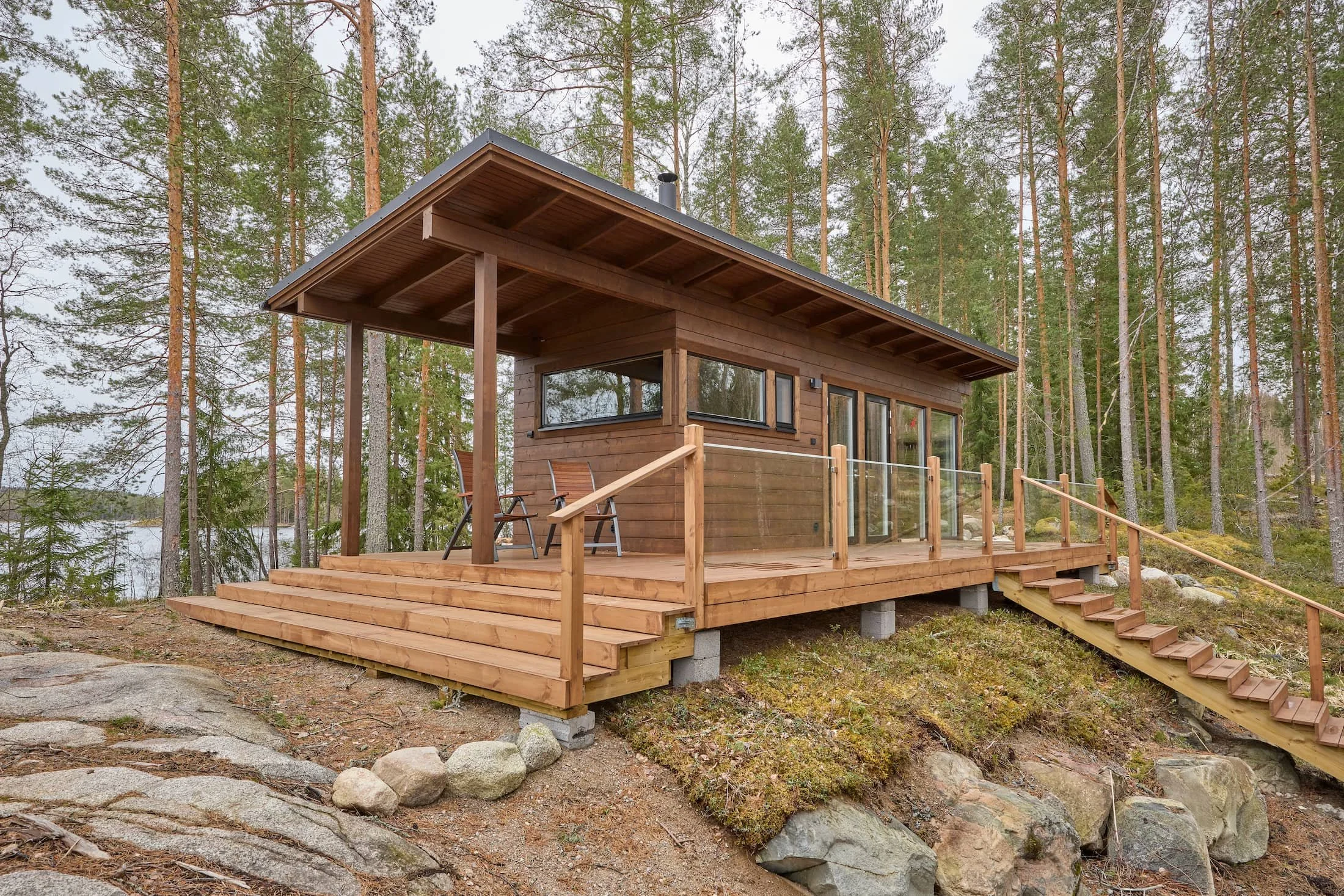 ruskea-moderni-hirsisauna-jarvenrannalla-kallion-paalla.jpg