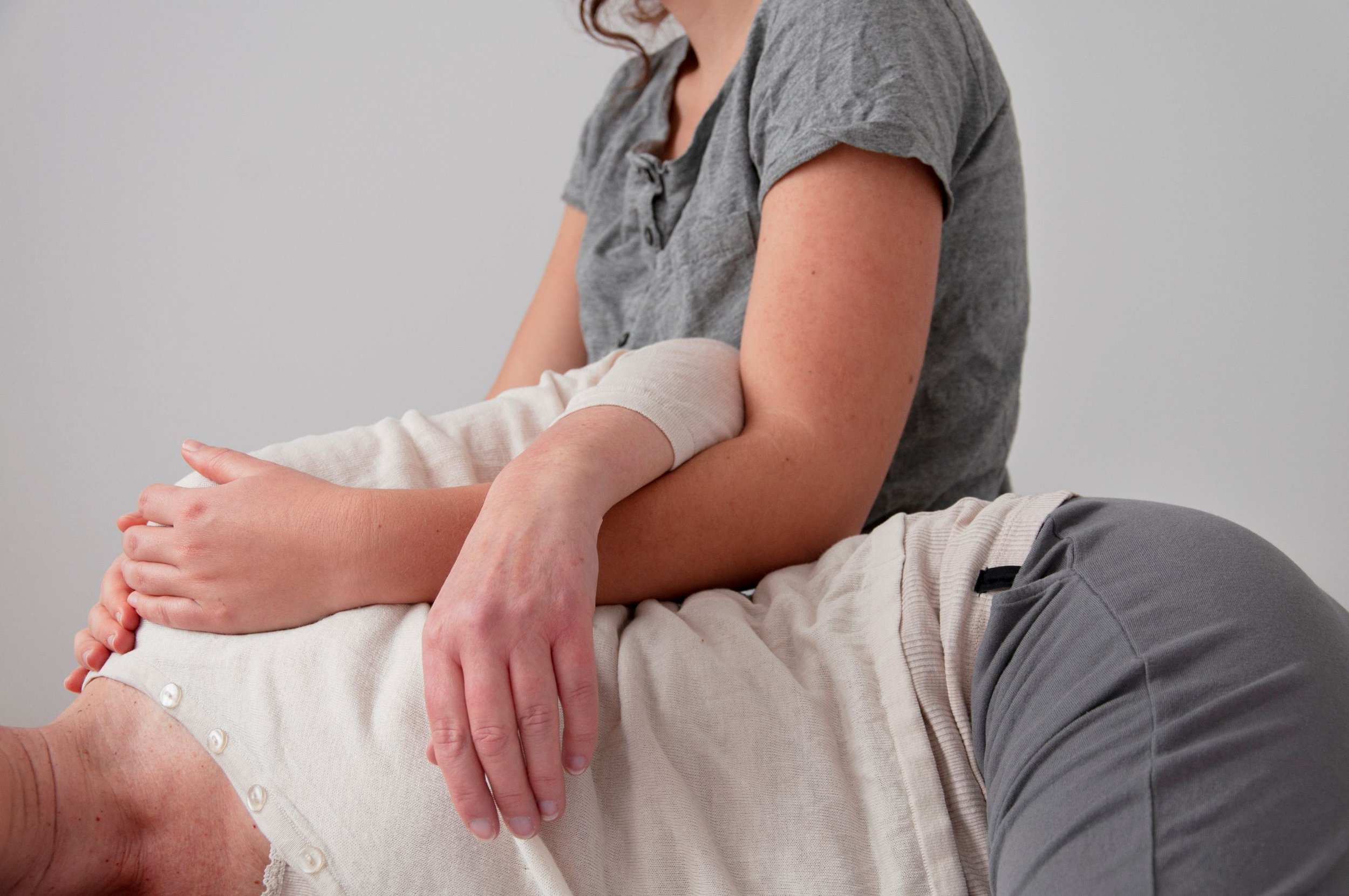 Eine Person liegt auf einer Liege, während eine andere Person sie professionell massiert, wahrscheinlich im Rahmen einer physiotherapeutischen Behandlung.