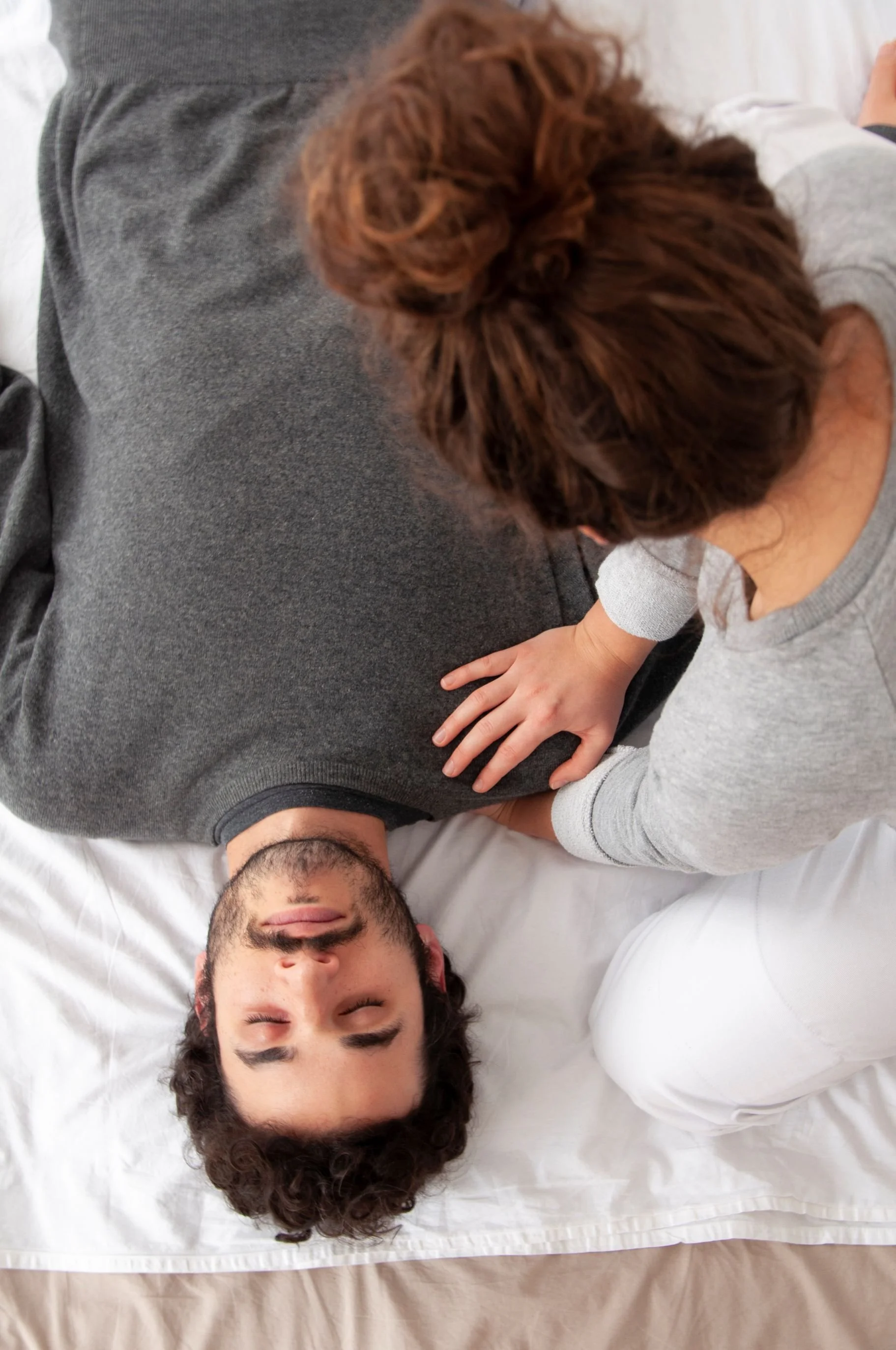 Jemand liegt auf einem Bett, während eine andere Person sie auf der Brust berührt.