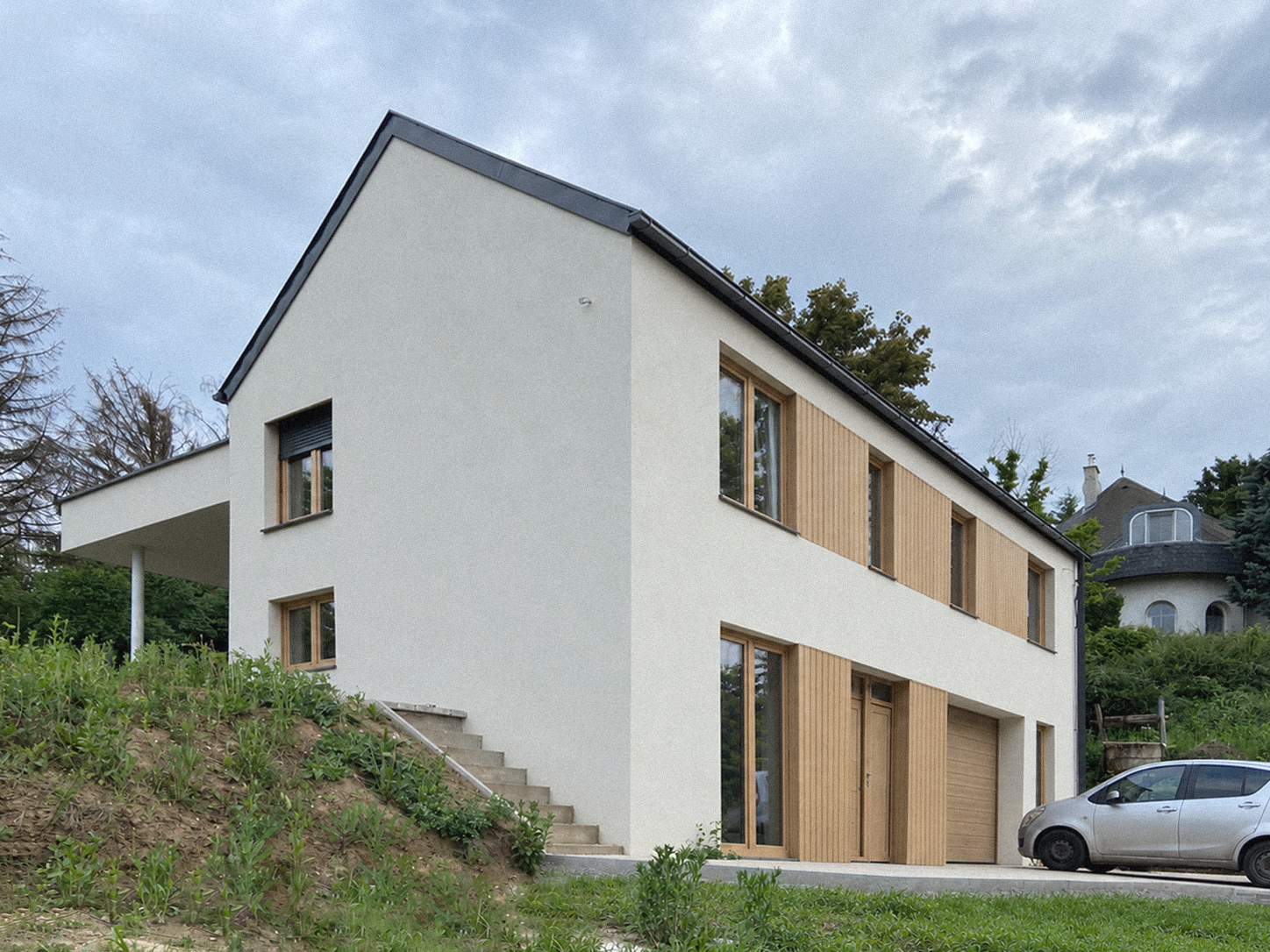 Modern, contemporary two-story house with flat roof, white exterior walls and wooden accents.