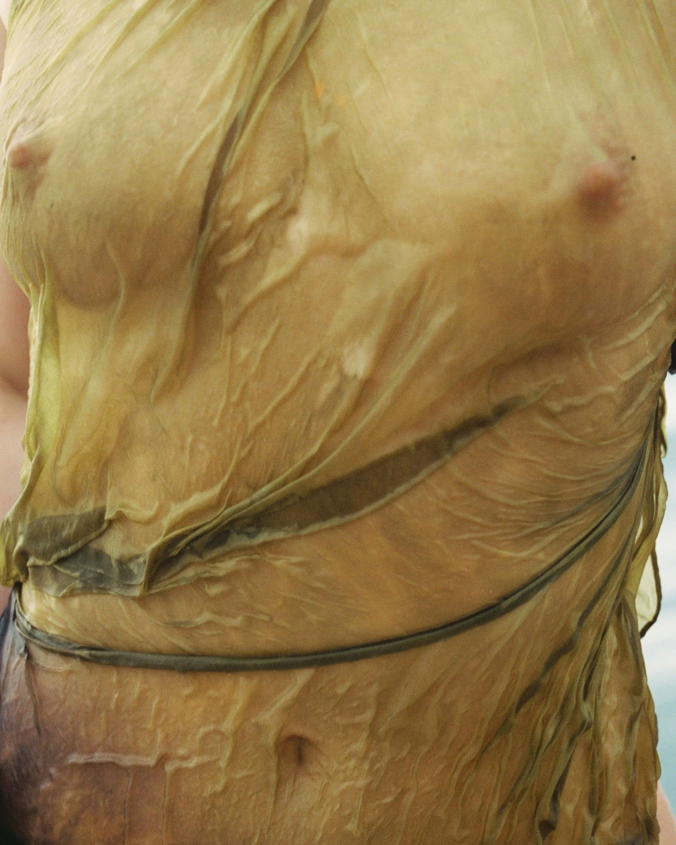 Close-up of a person wearing a yellow silk, exposing part of the chest and stomach.