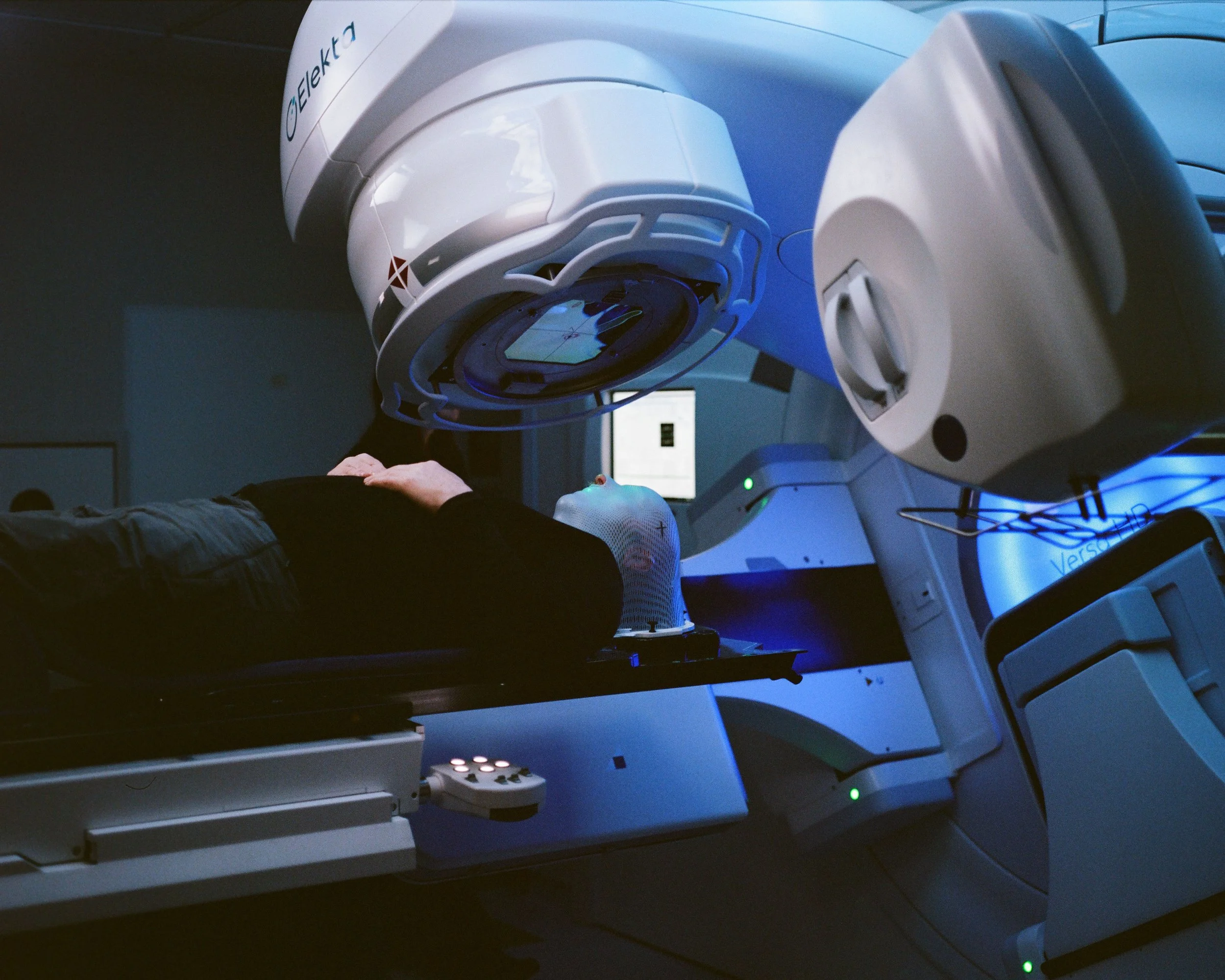 Person lying on a medical table inside a radiation therapy machine.
