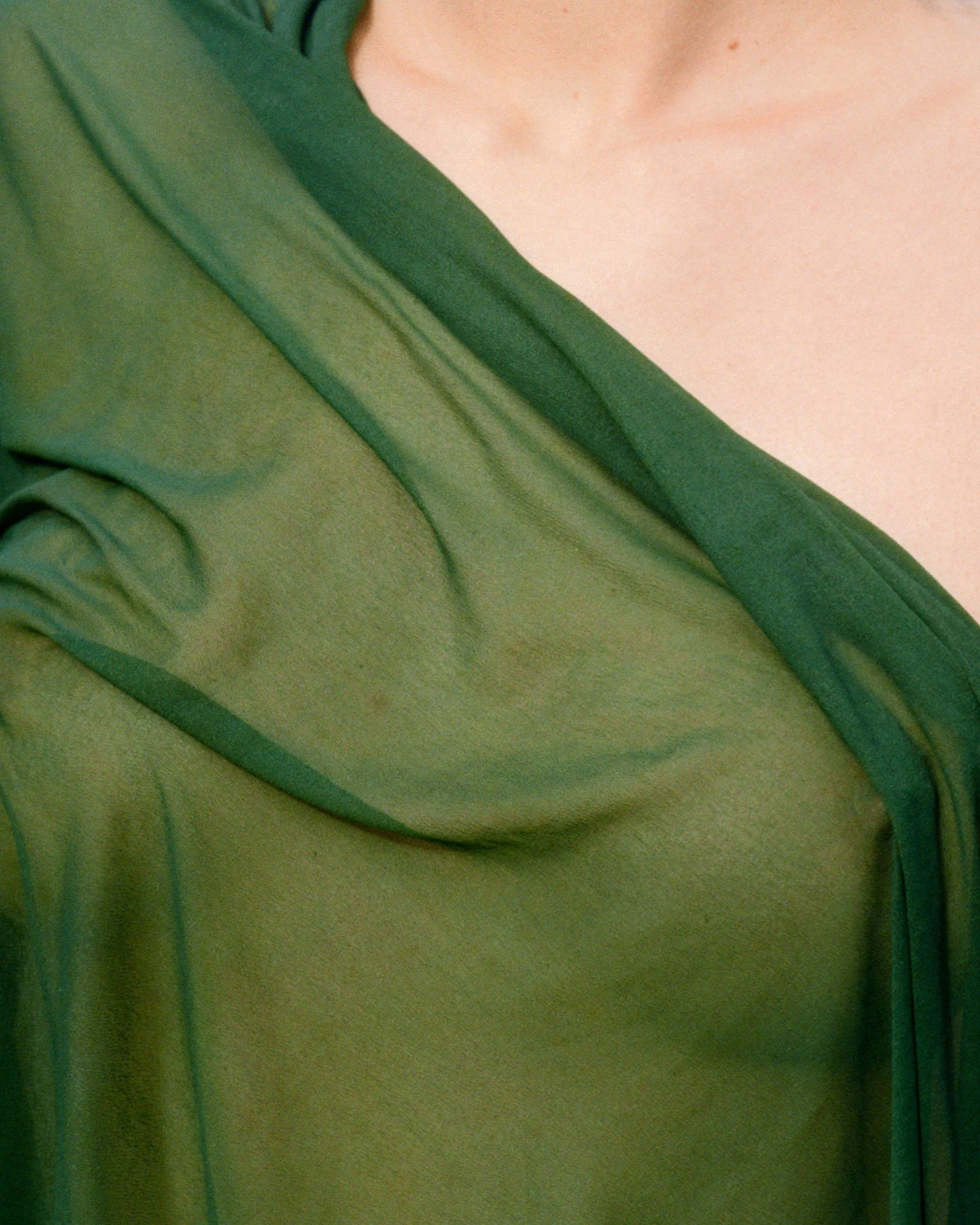 Close-up of a person wearing a green shirt, showing part of the shoulder and neckline.
