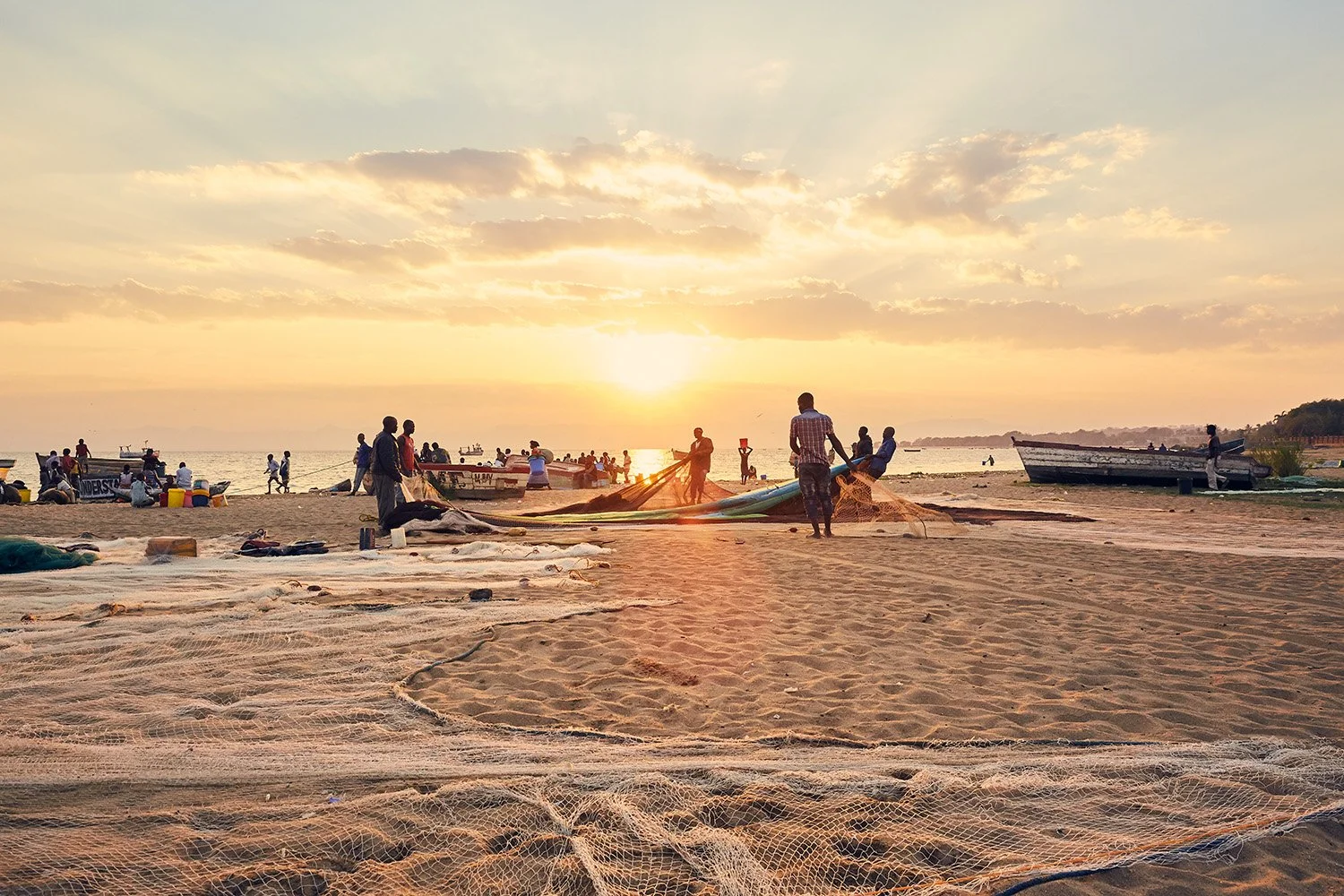 Shortly after dawn, fishermen untangle and lay out their nets, Makawa beach, Mangochi, Lake Malawi.