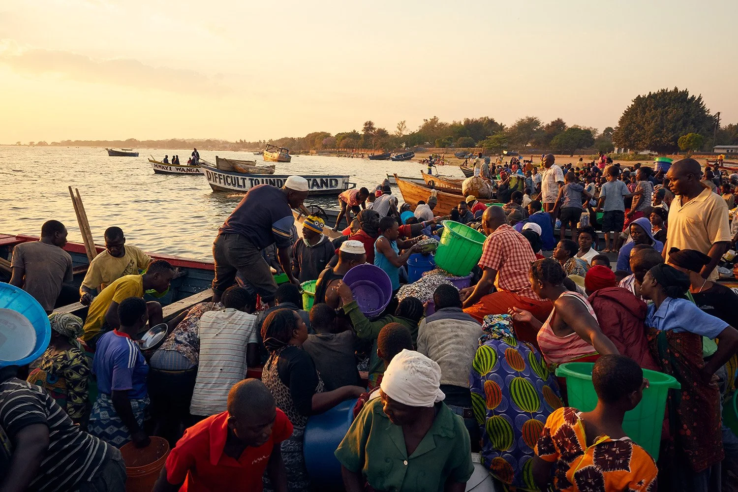 Fish traders crowd around boats which have just landed after the previous night’s fishing, Makawa beach, Mangochi, Lake Malawi.