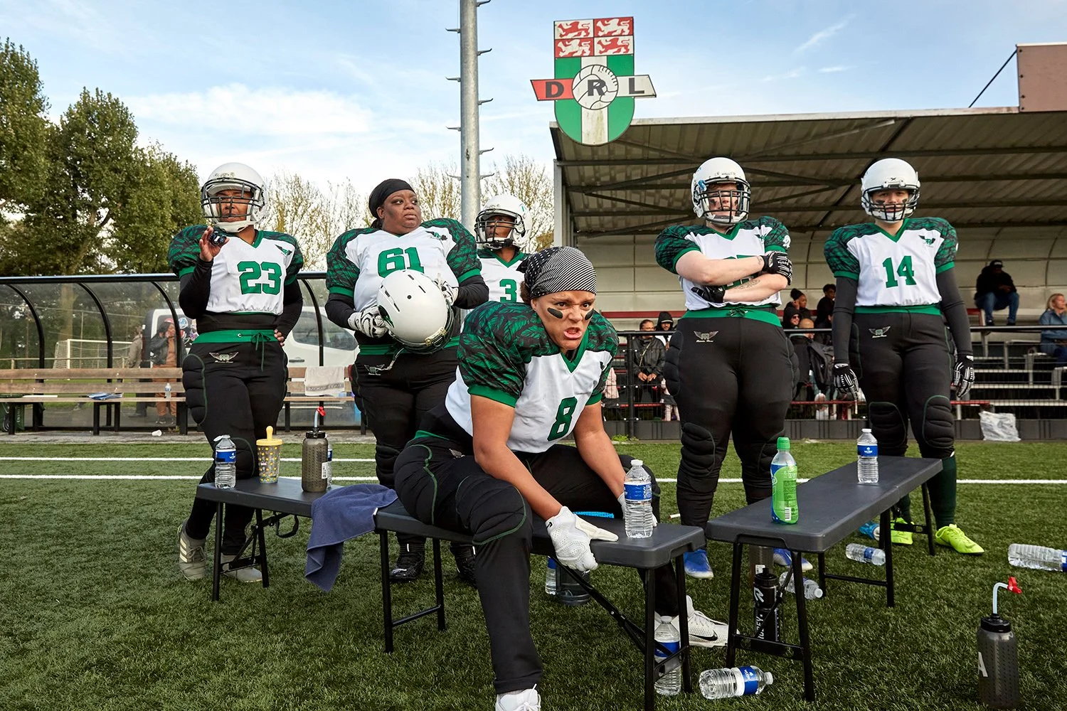 Together with her teammates, Dalila, a defensive end for the Rotterdam Ravens (center foreground), looks on as the Ravens' offense plays against the Eindhoven Valkyries, Rotterdam, NL, 2021.