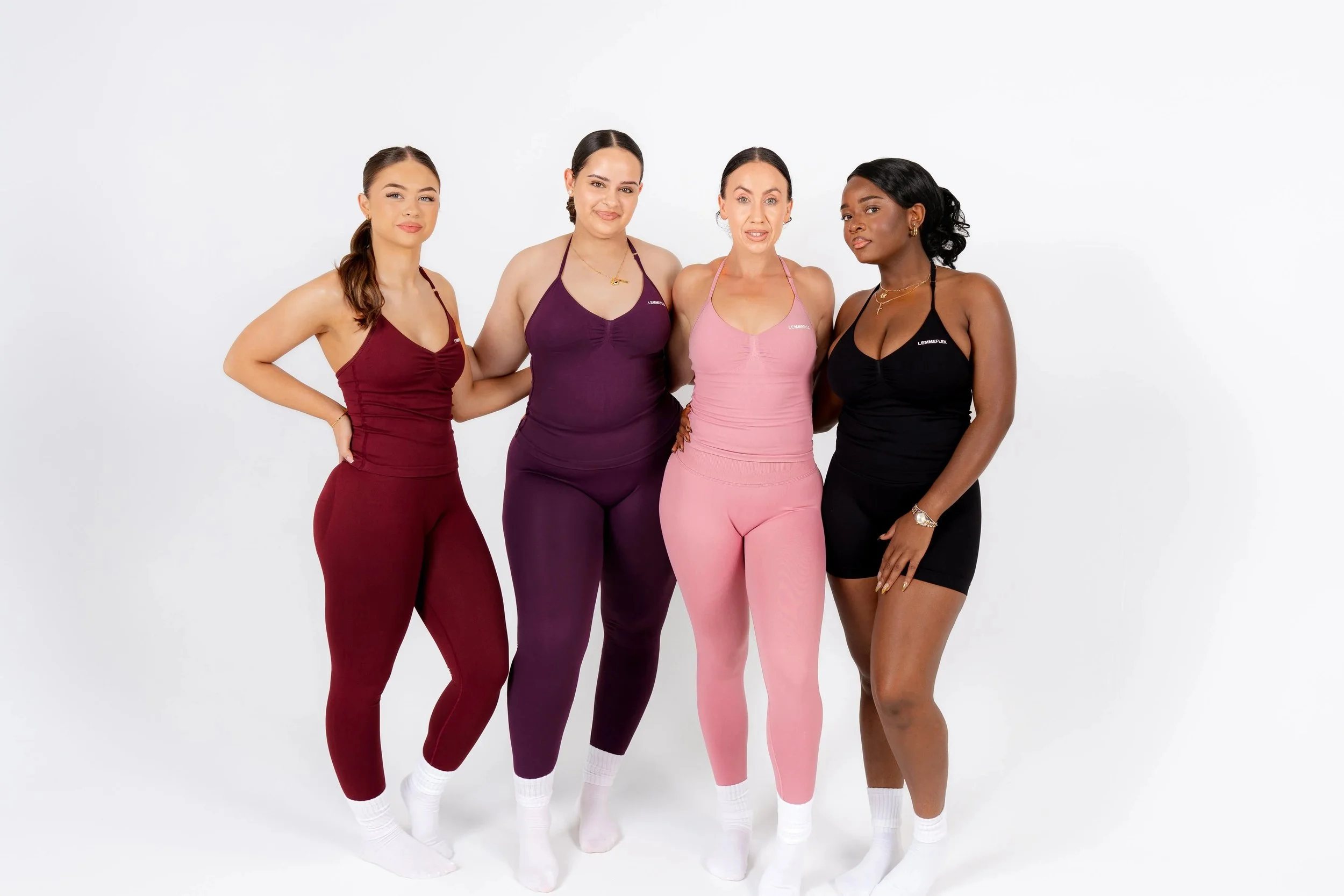 Four women standing side by side in form-fitting activewear, posing against a plain white background.