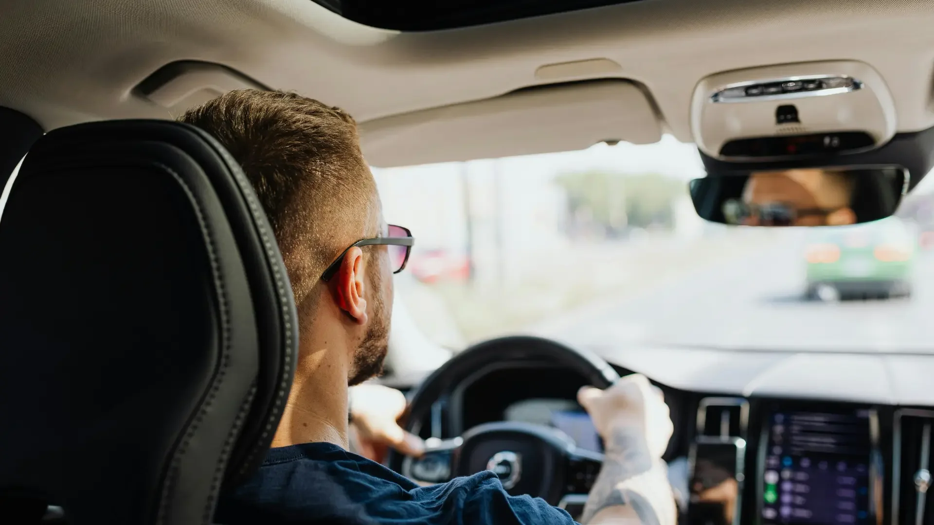 A man with glasses is driving a car