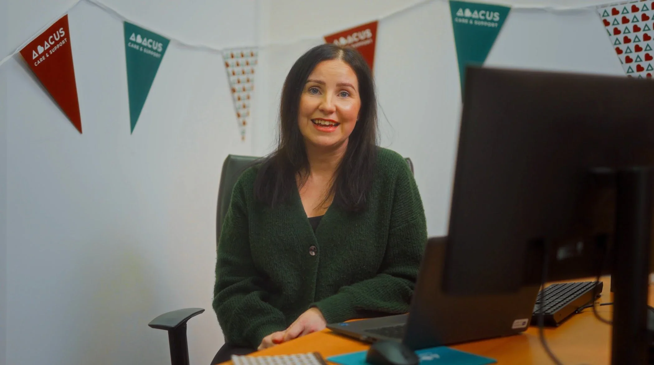 A staff member sits at a desk in front of Abacus branded bunting.