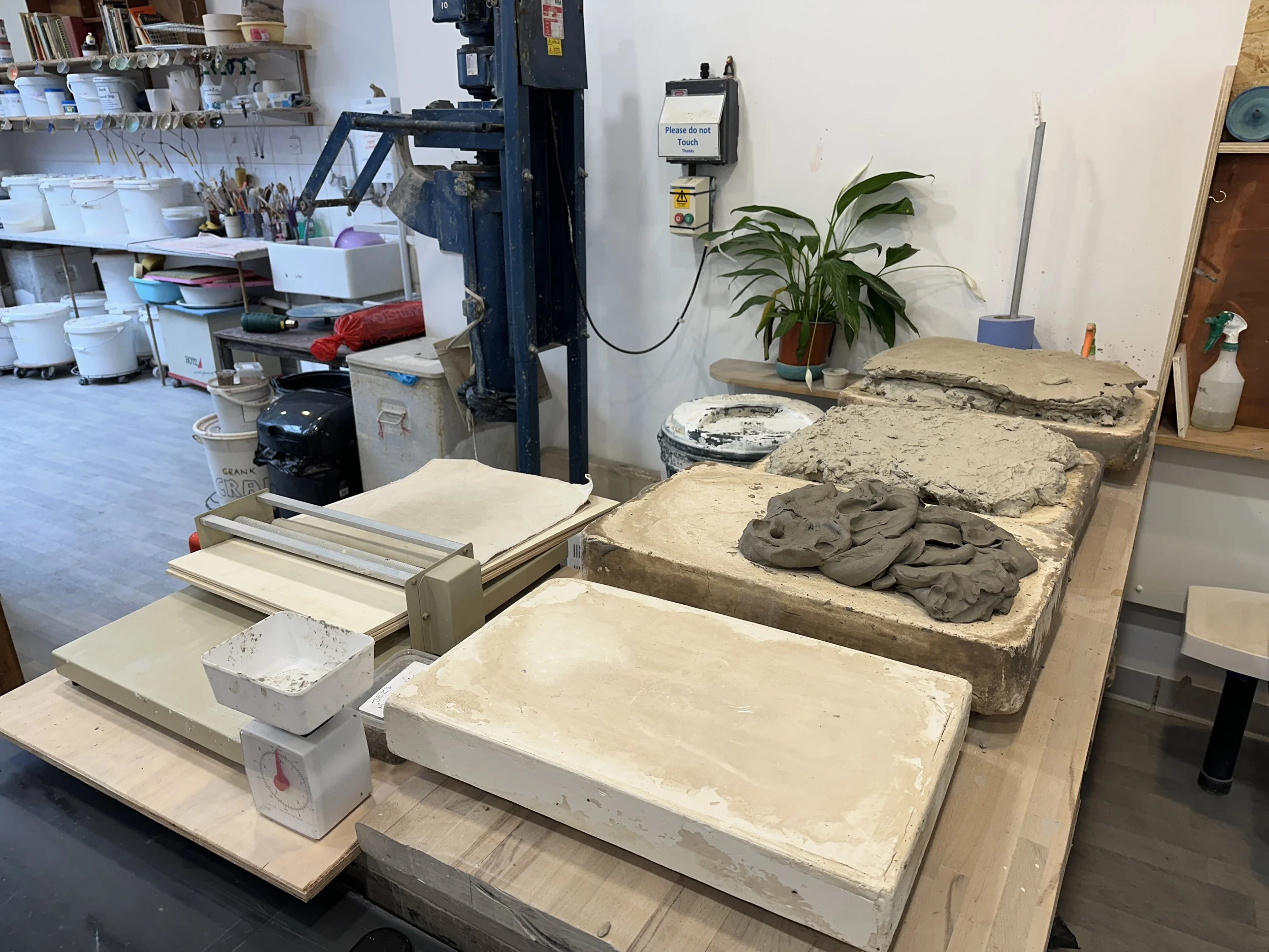 Art studio with pottery wheels, sculpting tools, and unfinished ceramic pieces on tables.