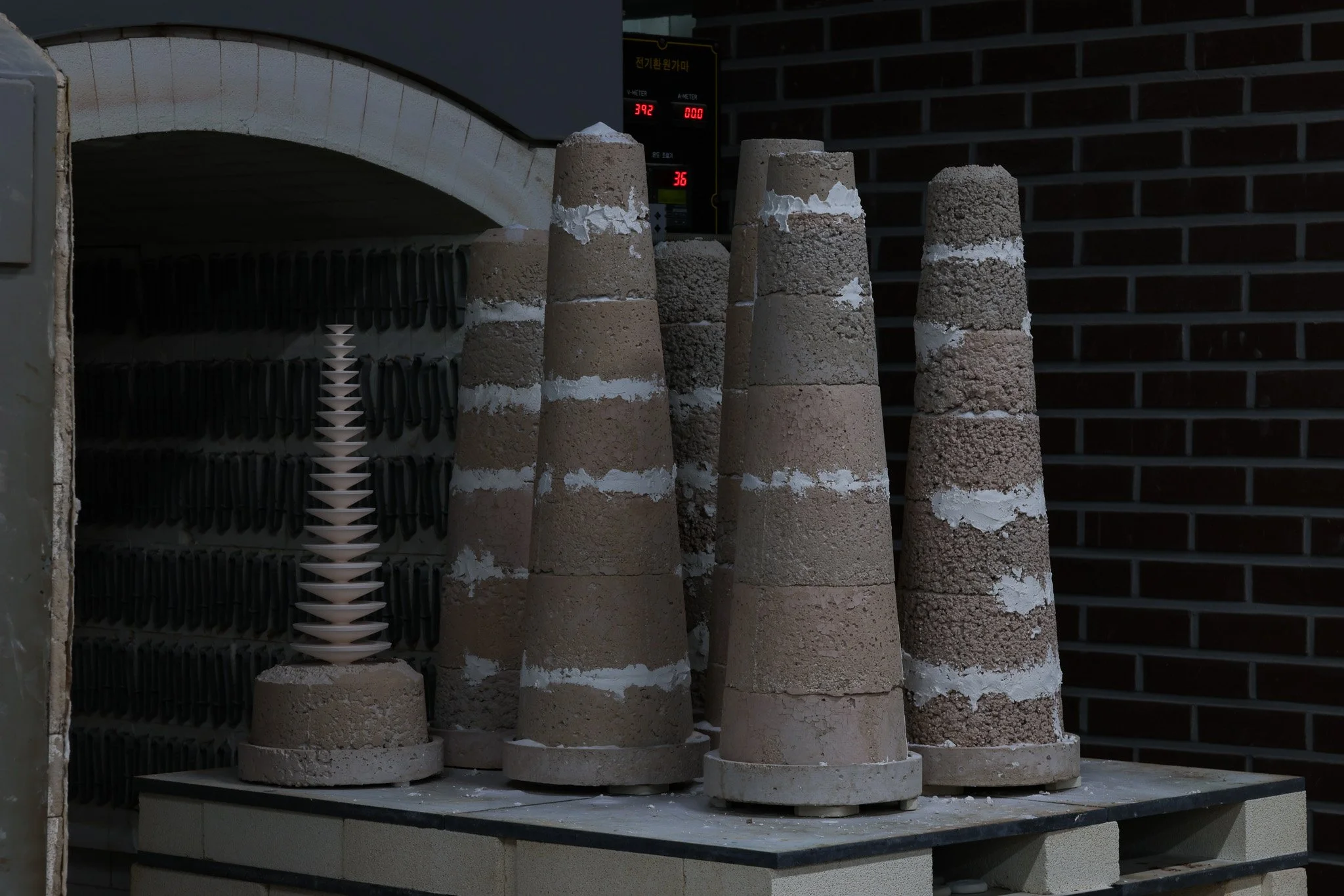 Several concrete cones stacked on a table, with a small white spiral sculpture on one of the cones, in an industrial or testing environment.