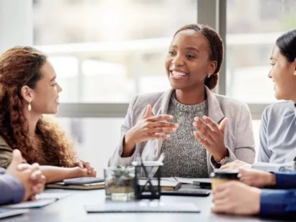 Women in a discussion during a group safeguarding supervision sessionmeeting in a bright school office.