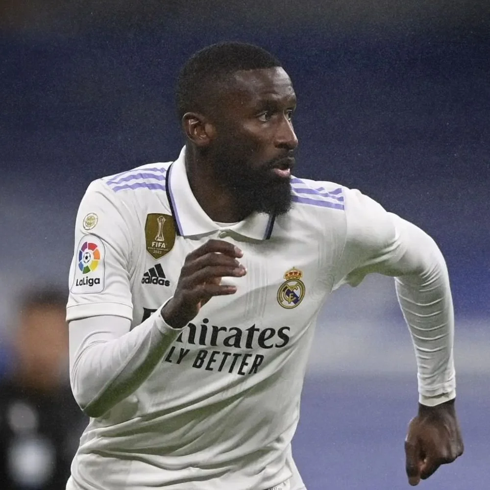 A soccer player in a white Real Madrid jersey running during a match.