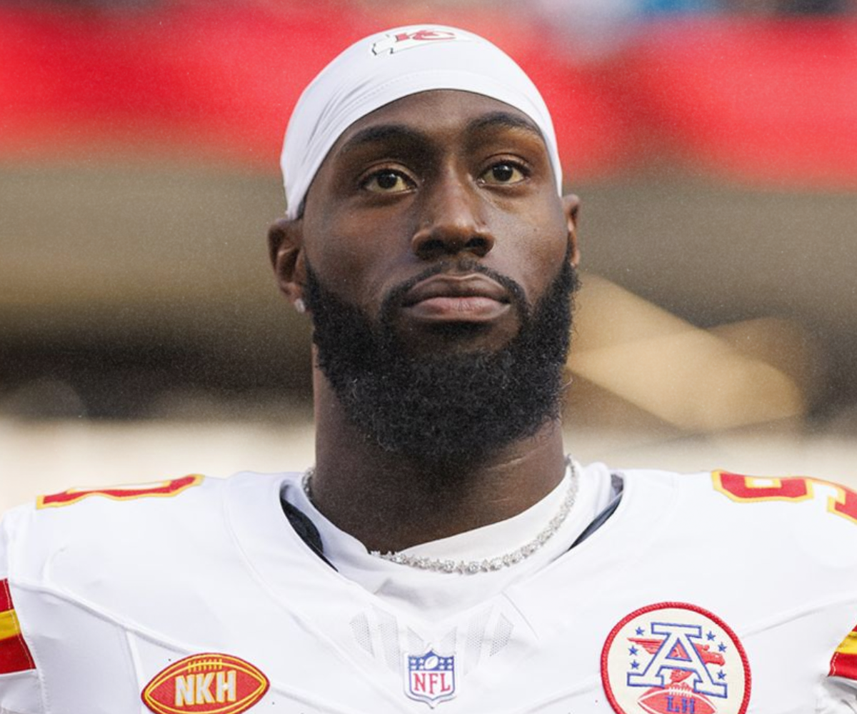Close-up of a man wearing a white football jersey and a white headband, with a serious expression on his face.