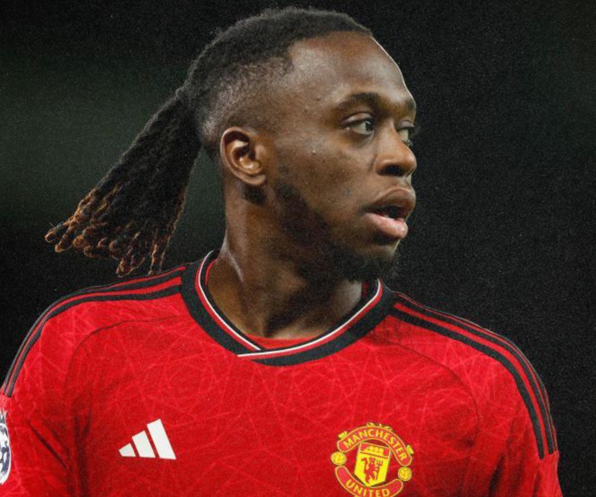 A soccer player in a red Manchester United jersey with black and gold accents, looking to the right.