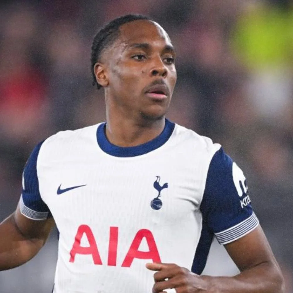 A male soccer player wearing a white and navy blue Tottenham Hotspur jersey on the field during a game.