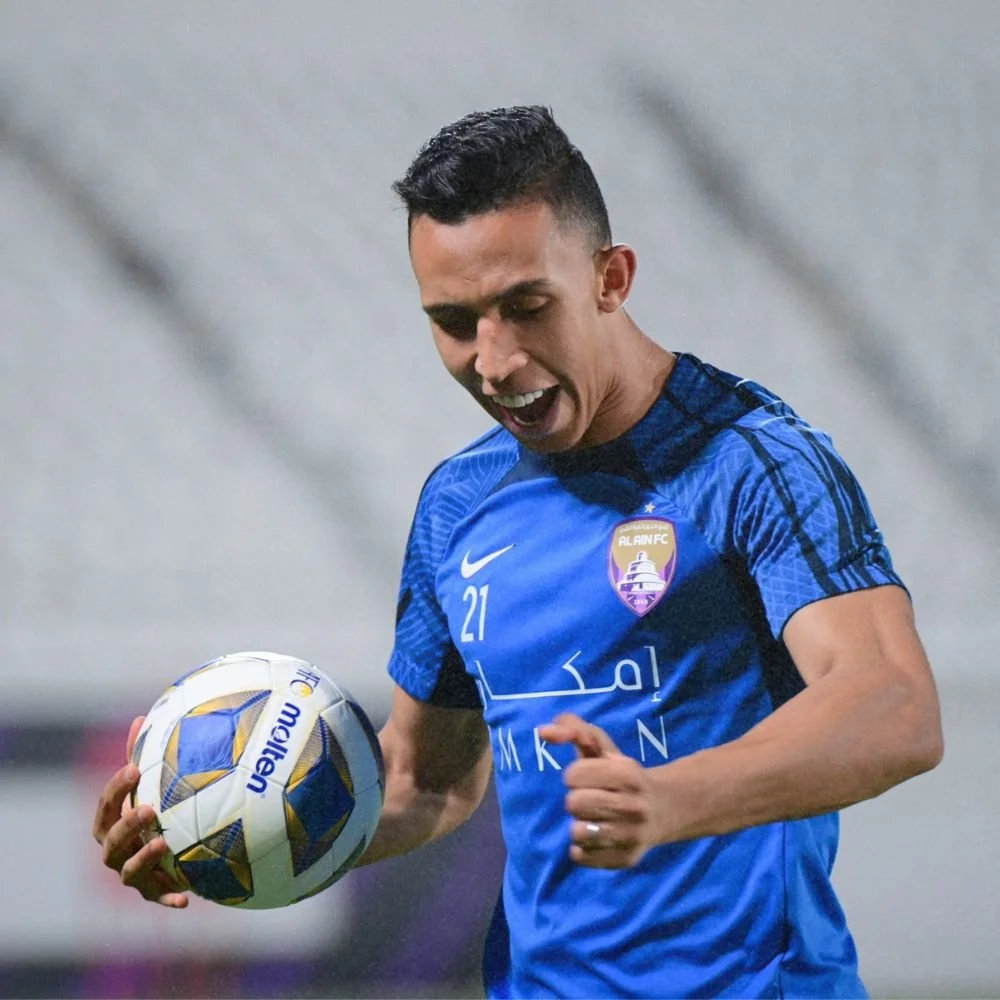A soccer player in a blue jersey holding a ball on a field.