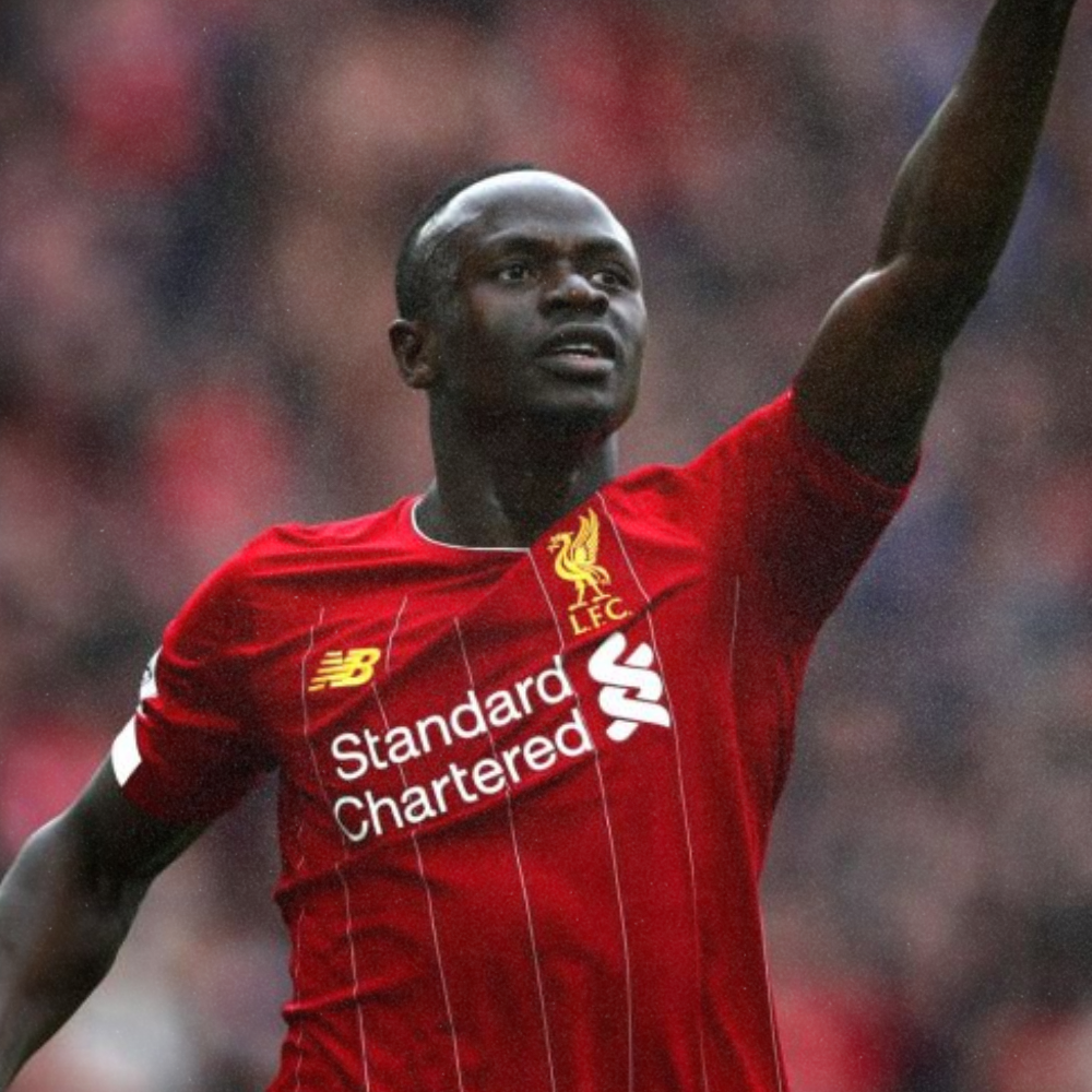 A male soccer player in a red Liverpool jersey celebrating on the field.