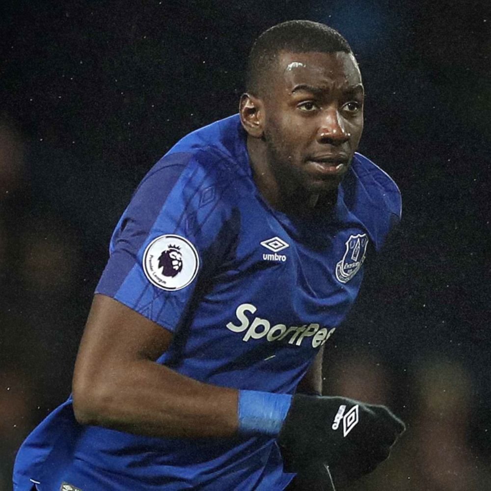 A male soccer player in a blue jersey with the Everton Football Club logo and a Premier League patch, running during a match.