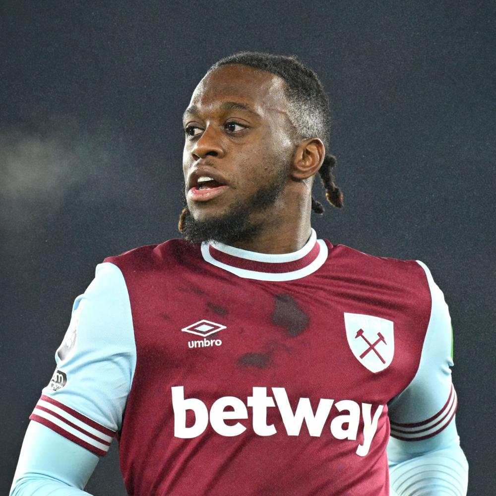 A soccer player in a maroon and light blue jersey, with the West Ham United logo, on a field during a match.