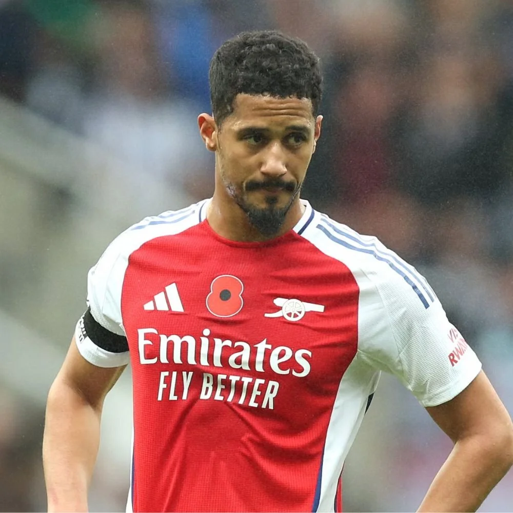 A male soccer player in an Arsenal jersey with red, white, and blue colors, standing on the field during a game.