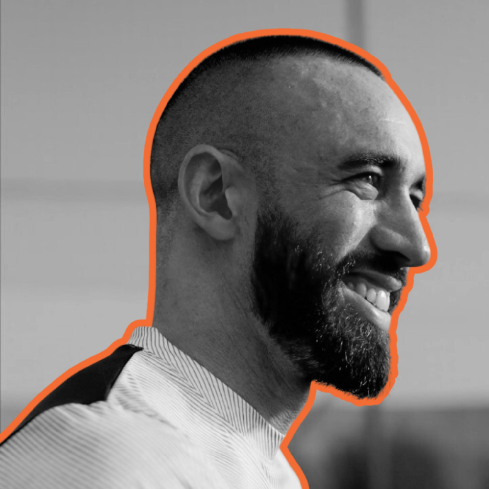 Profile of a smiling man with beard, short hair, wearing a shirt, outlined in orange, in black and white.