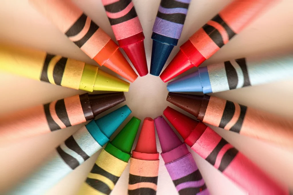 Colorful wax crayons arranged in a circle, pointing inward.