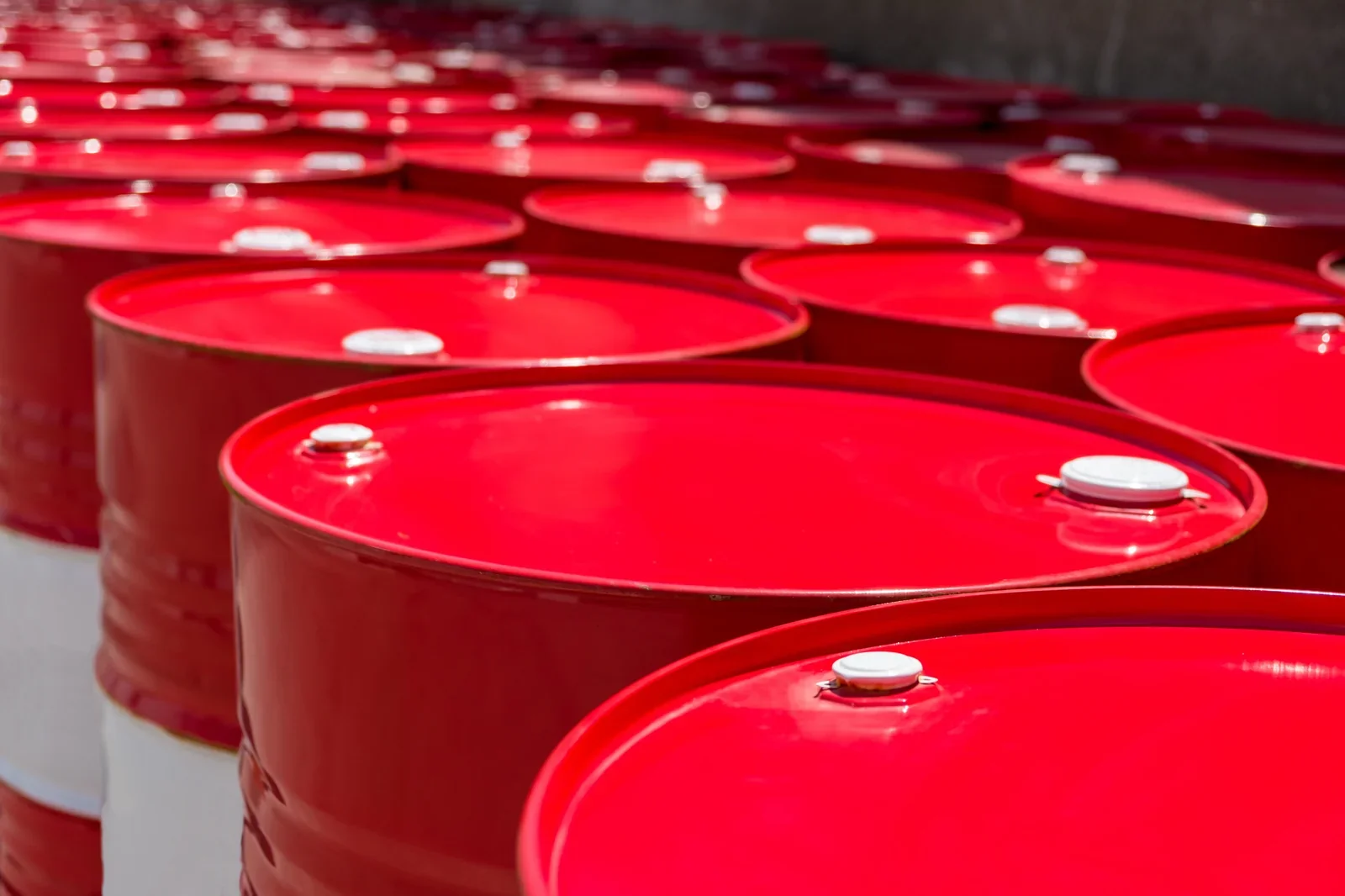 Multiple red barrels with white lids arranged in rows outdoors.