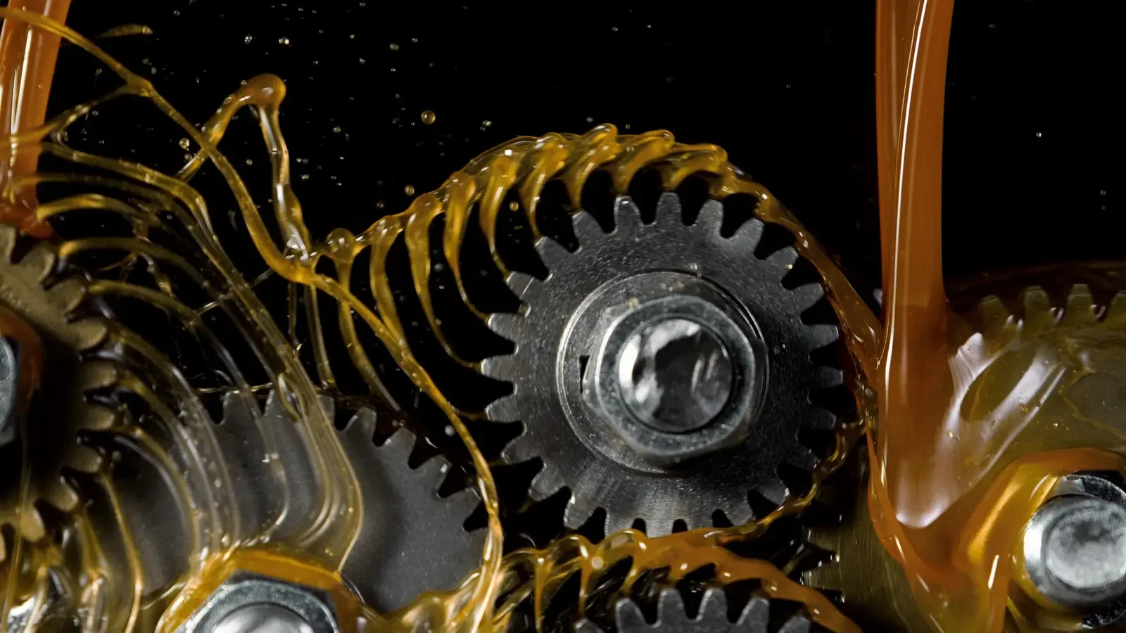 Close-up of gears and oil in a mechanical system, possibly part of a machine or engine.