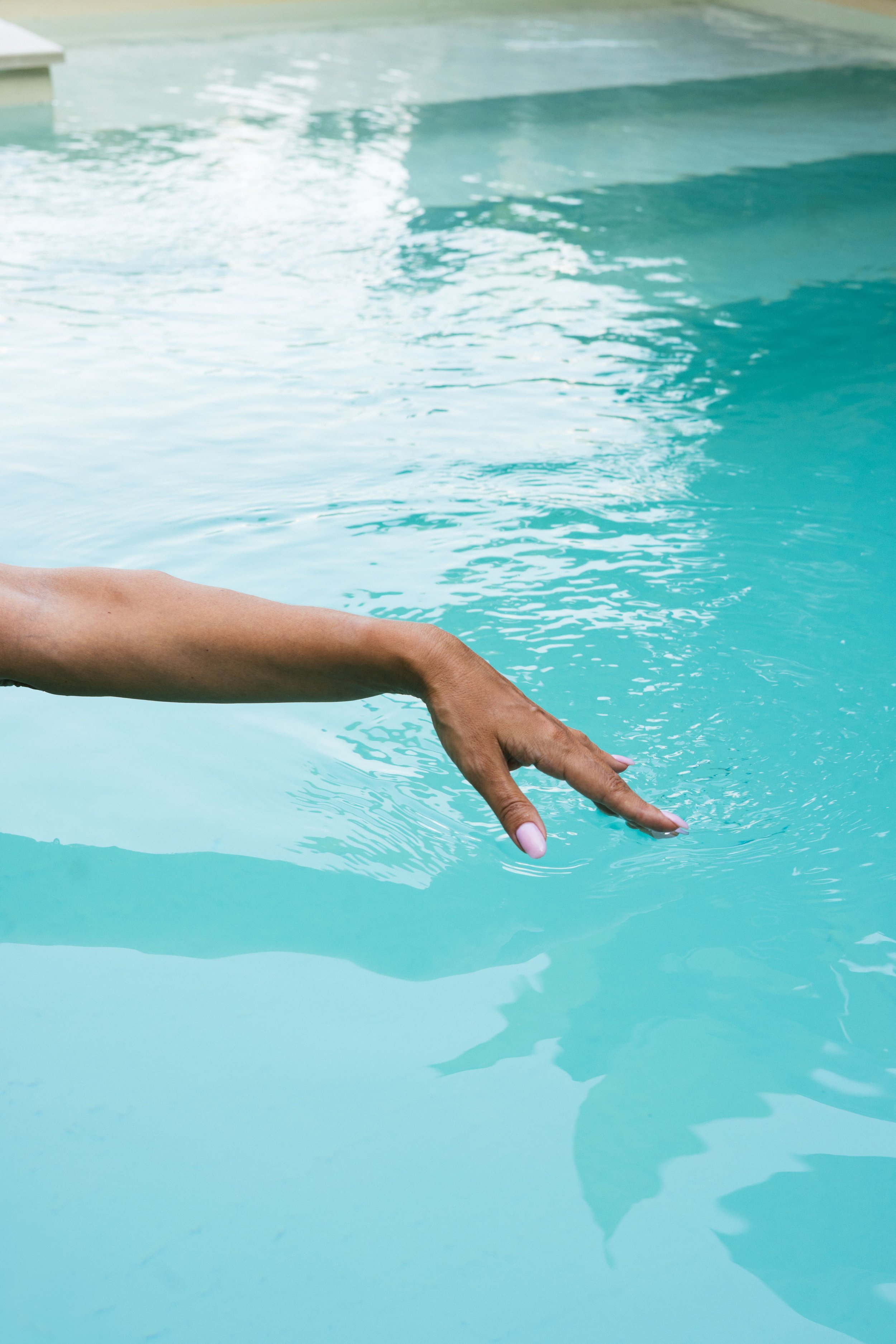 Ruka osobe delimično uronjena u bazen s bistrom plavom vodom. Bobana Simovic